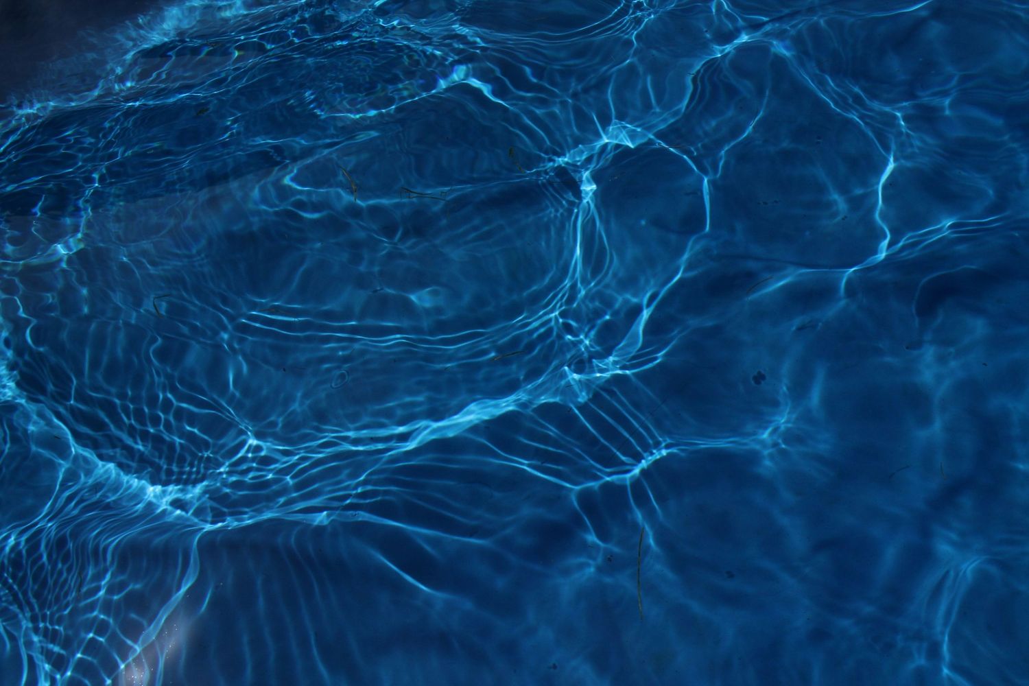 Electric blue water ripples creating abstract patterns in dark lighting.