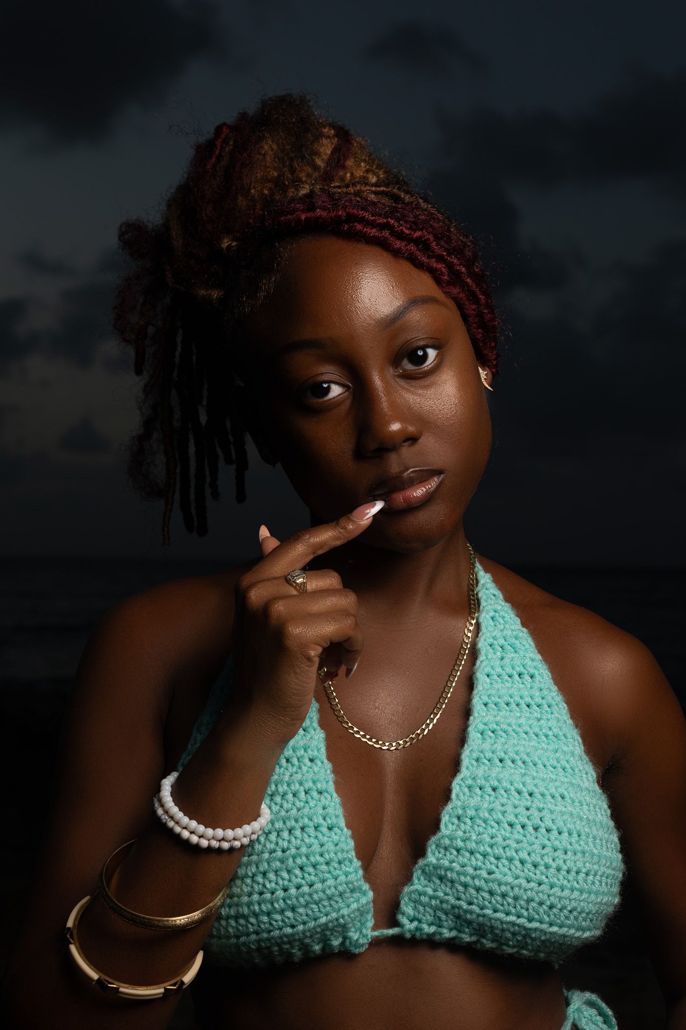 Portrait series showing someone in a mint green crochet top with gold jewelry against dark background.