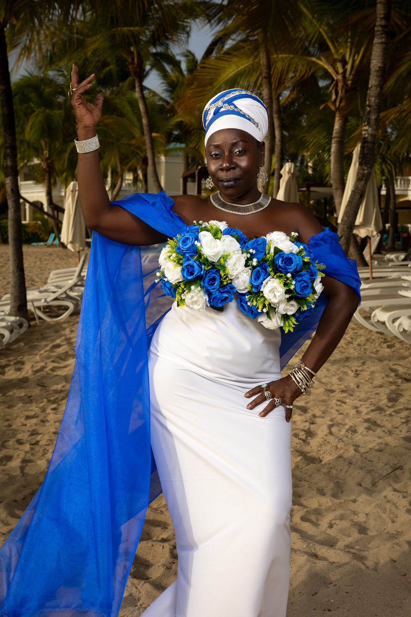Beachside photo series featuring white dress with blue cape and floral accents.