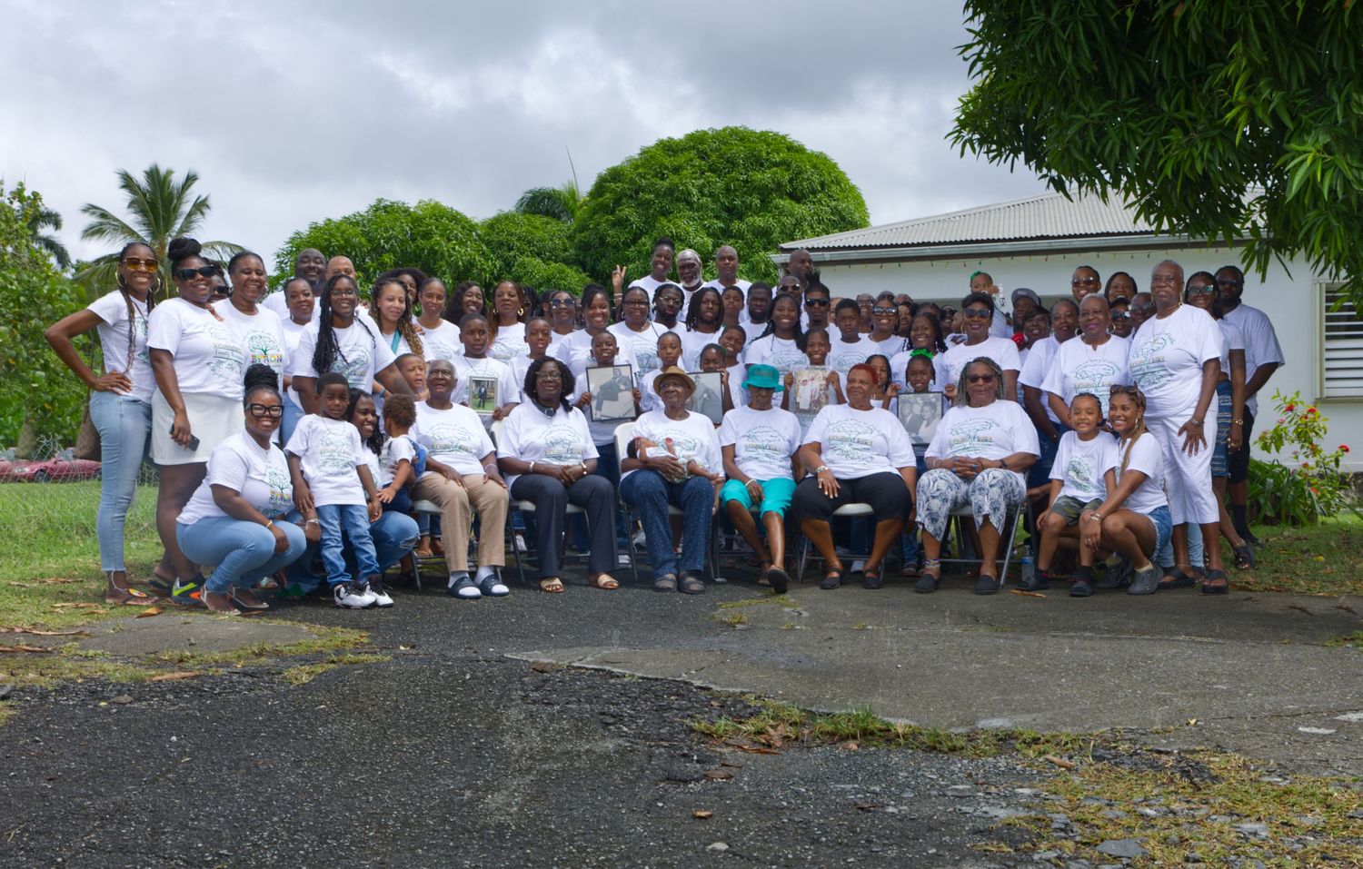 Large group photo of people wearing white shirts gathered outdoors on a sunny day.