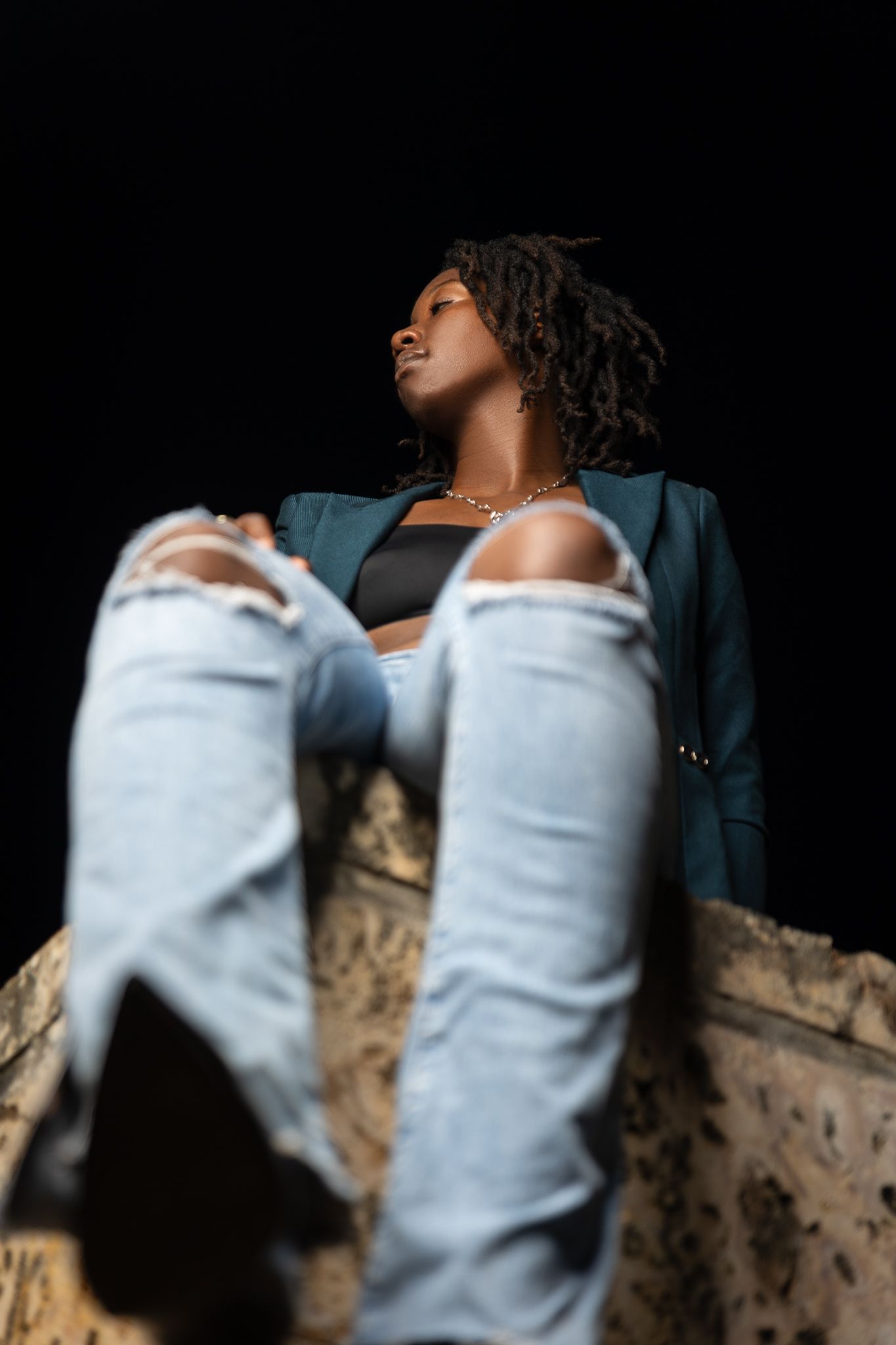 Artistic portrait series featuring ripped jeans and casual pose against dark background.
