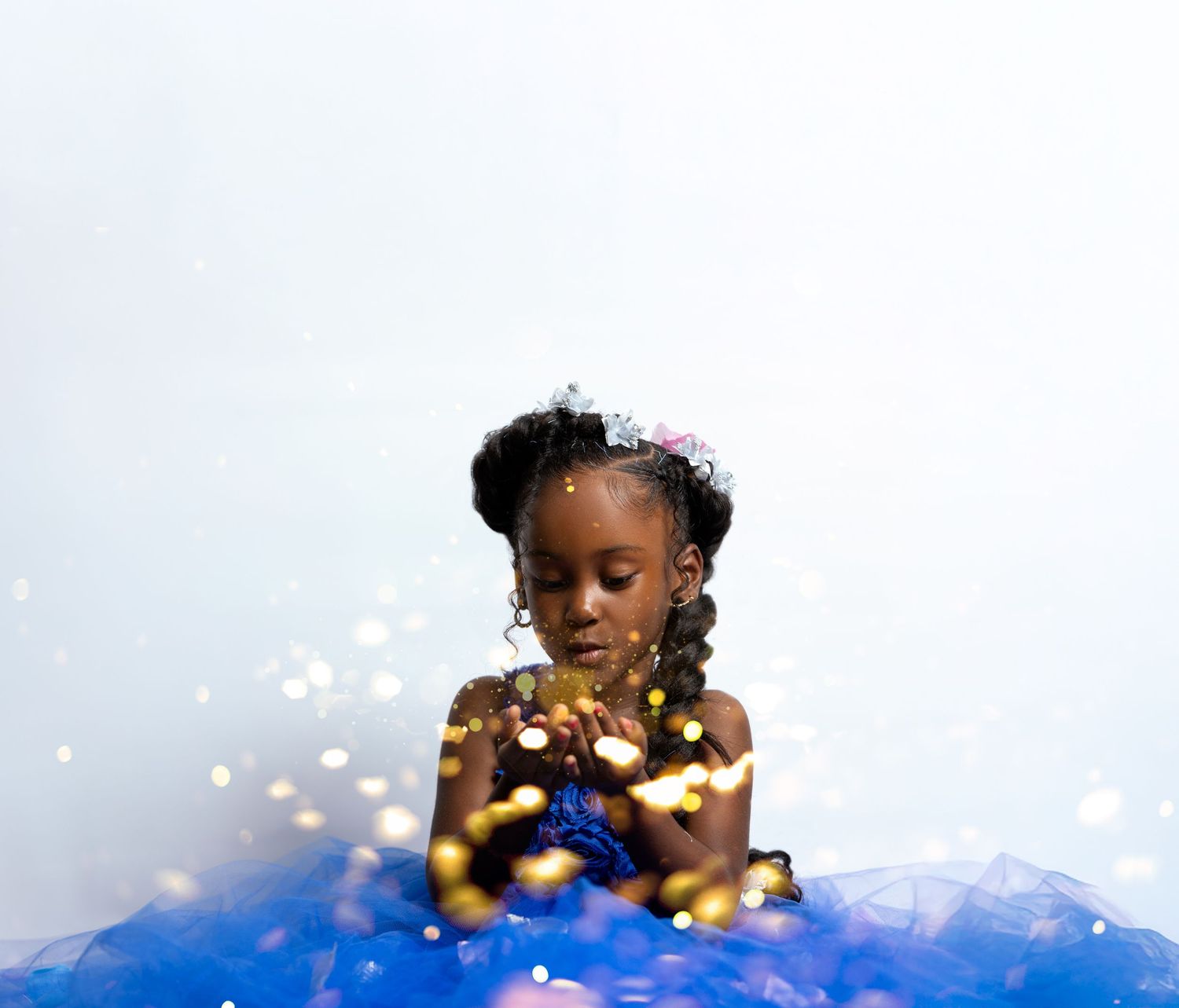 Child in a blue tulle dress with fairy lights creating a magical effect.