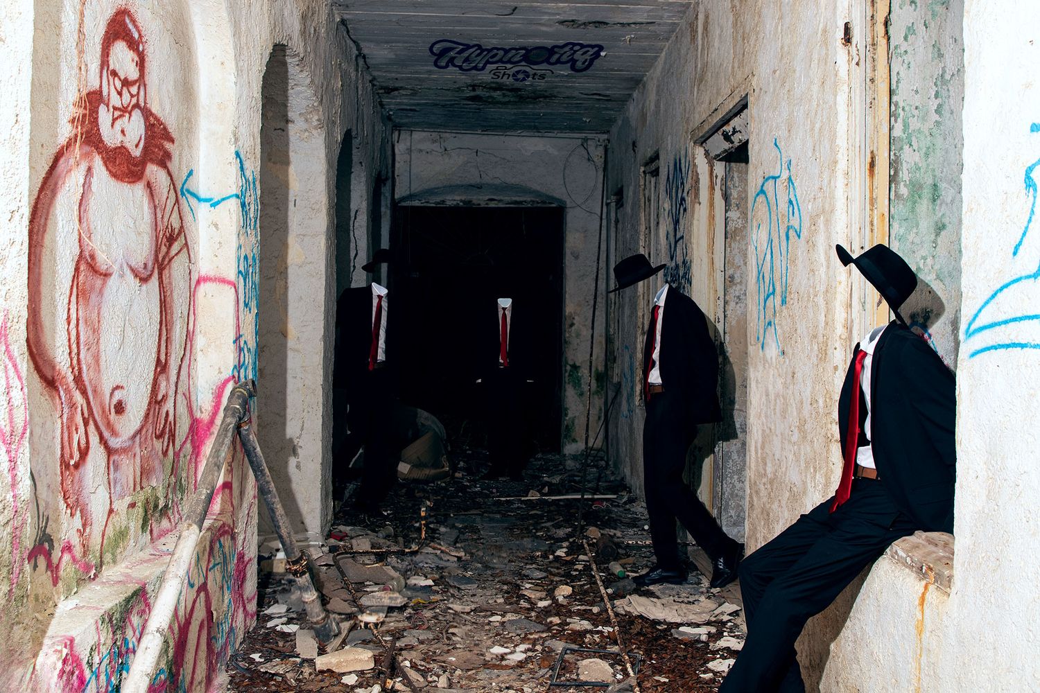 Long dark corridor in a dilapidated building with peeling walls and graffiti art.