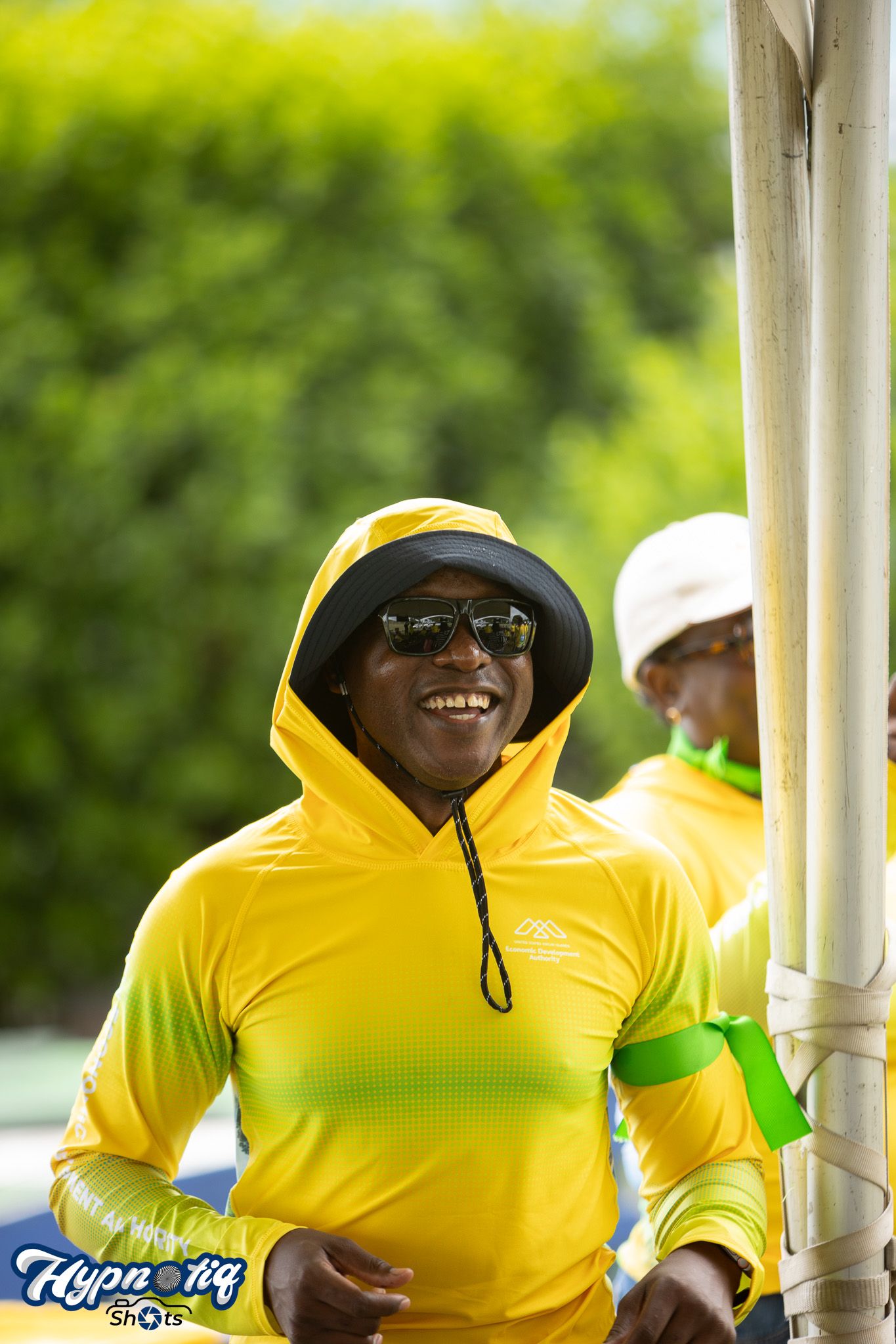 Row of people in yellow uniforms standing under a white gazebo.