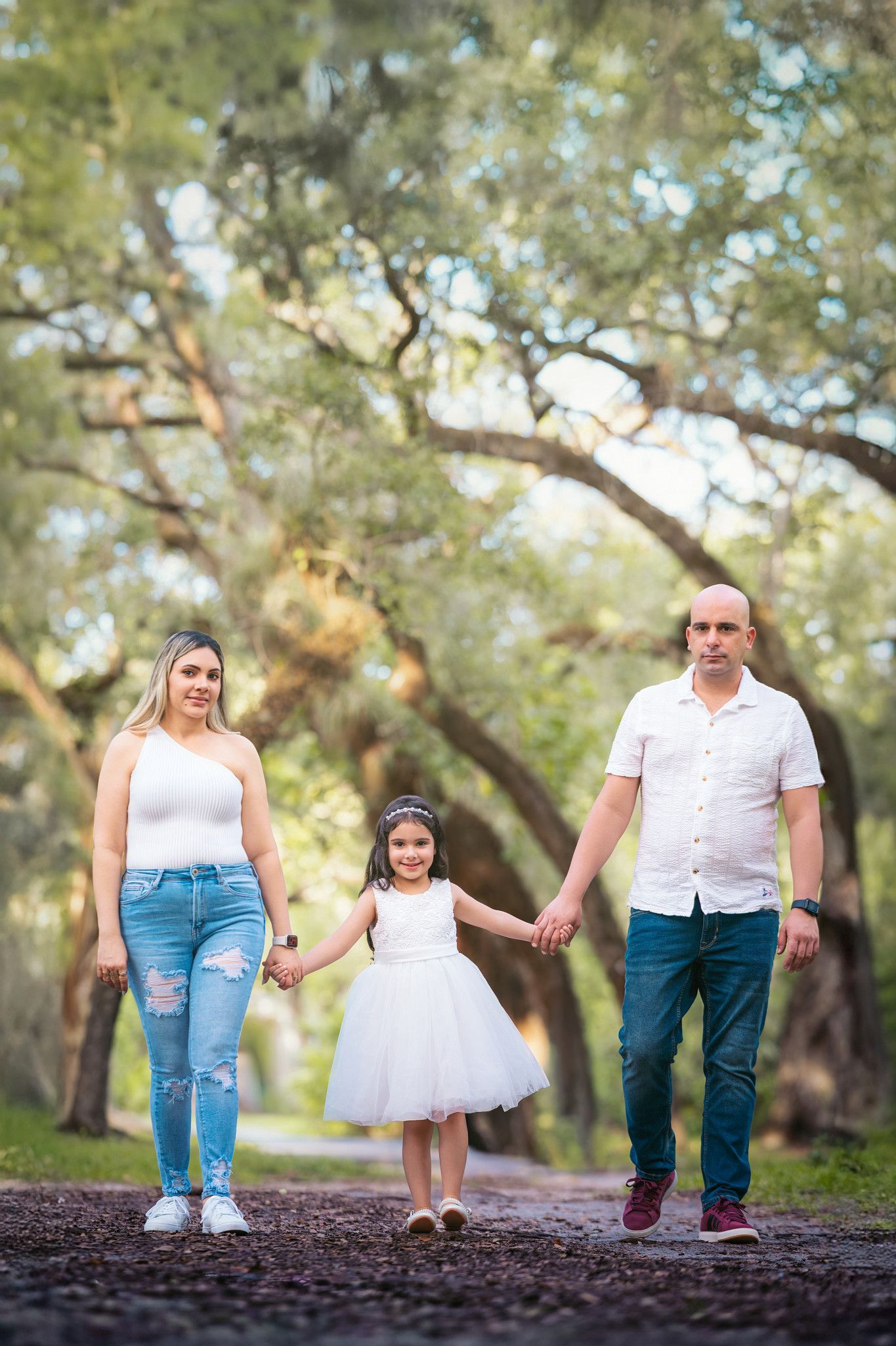 A family walks together along a raised path surrounding by tall trees.