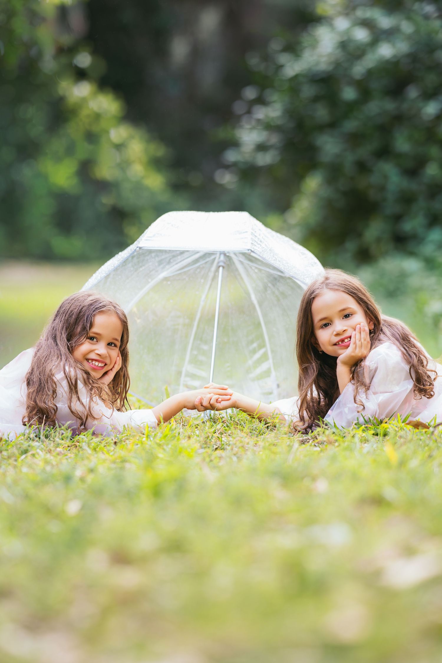 A sequence of four photos showing someone lying in grass with a clear umbrella, creating a playful outdoor portrait series.