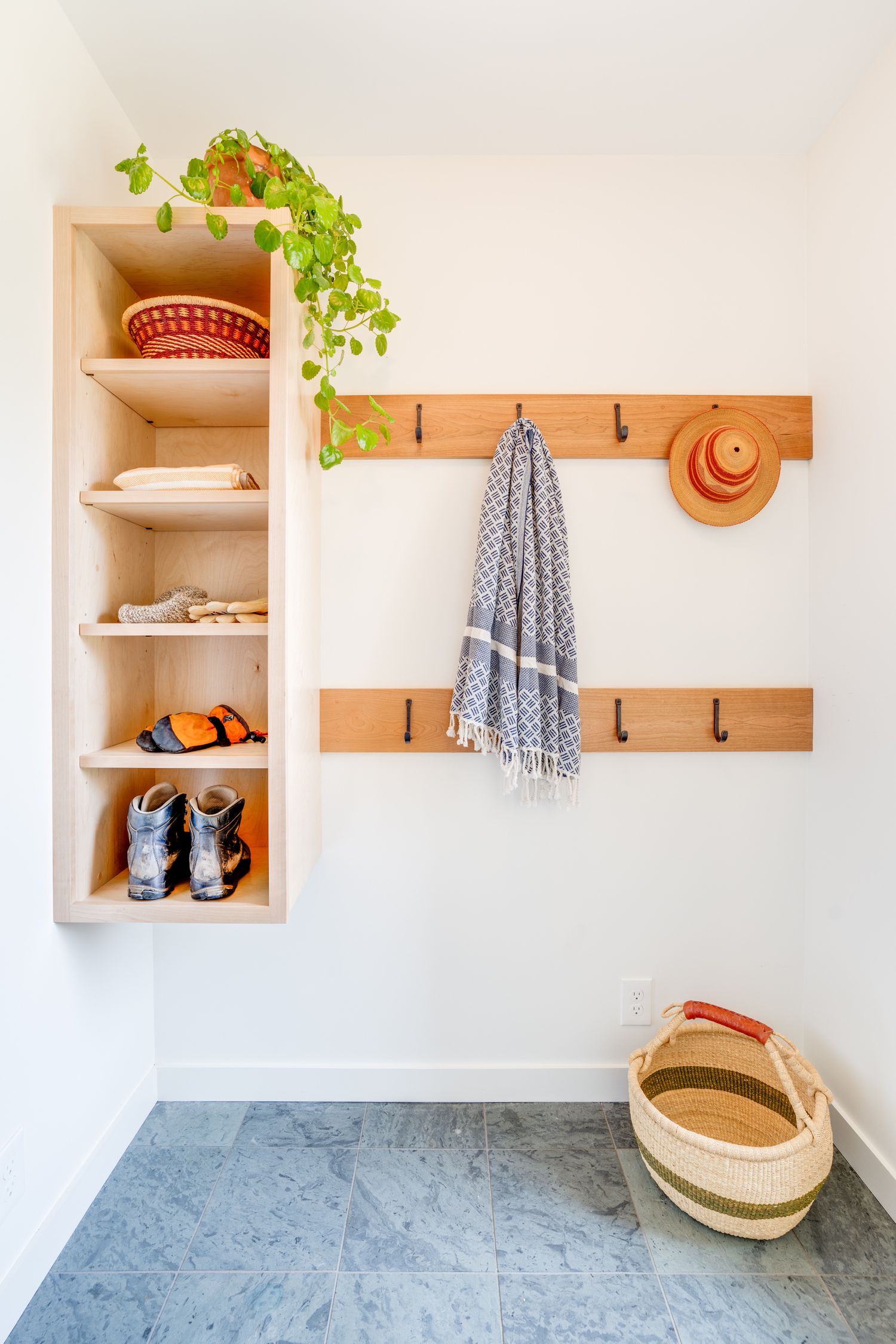 Organized mudroom entry with built-in shelving, wooden coat hooks, and decorative straw hat wall decor.