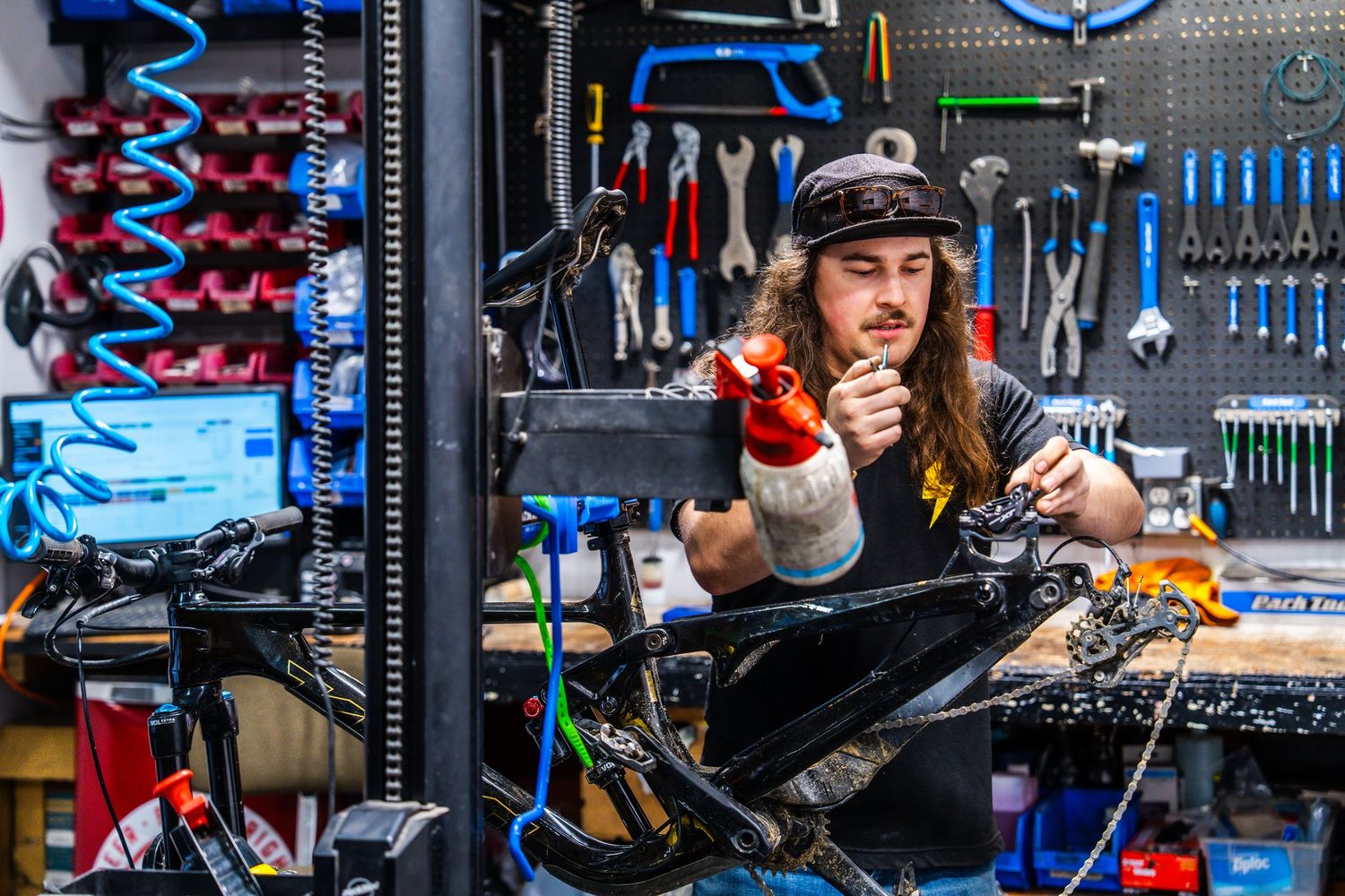 Technician working on electronic components at a well-organized workbench with blue-lit tools and equipment.