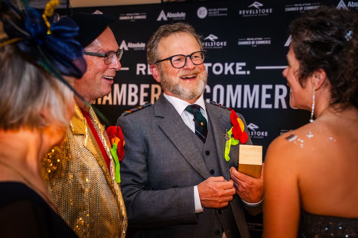 A group of people in formal attire share laughter and conversation at an elegant evening event.