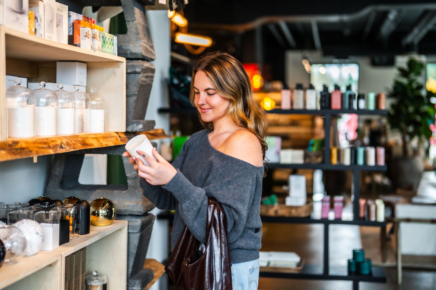 Customer browsing products on wooden shelves in a modern retail store with indoor plants.