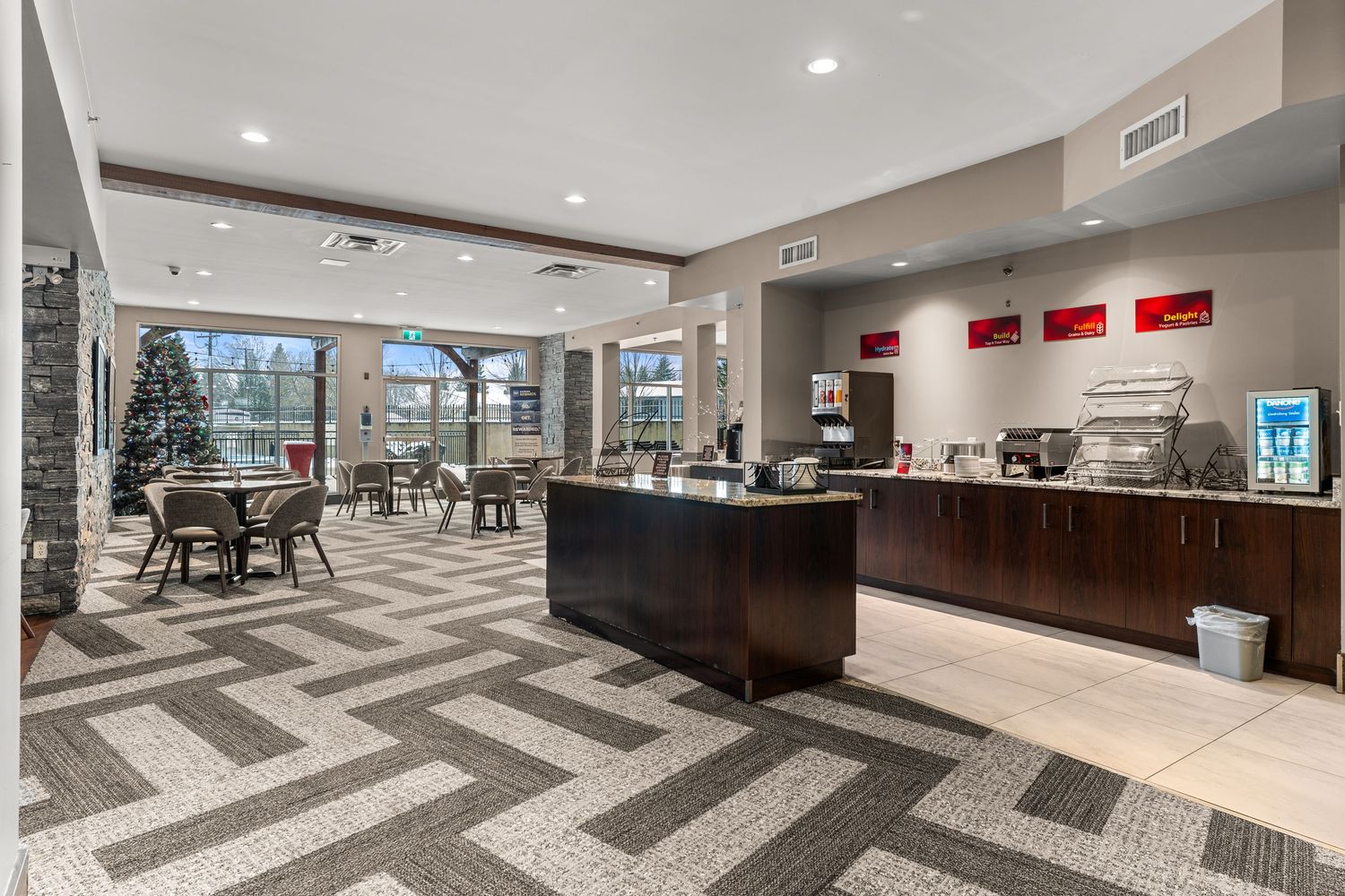 Modern office lobby with chevron patterned carpet, dark wood accents, and recessed lighting creates an elegant workspace atmosphere.