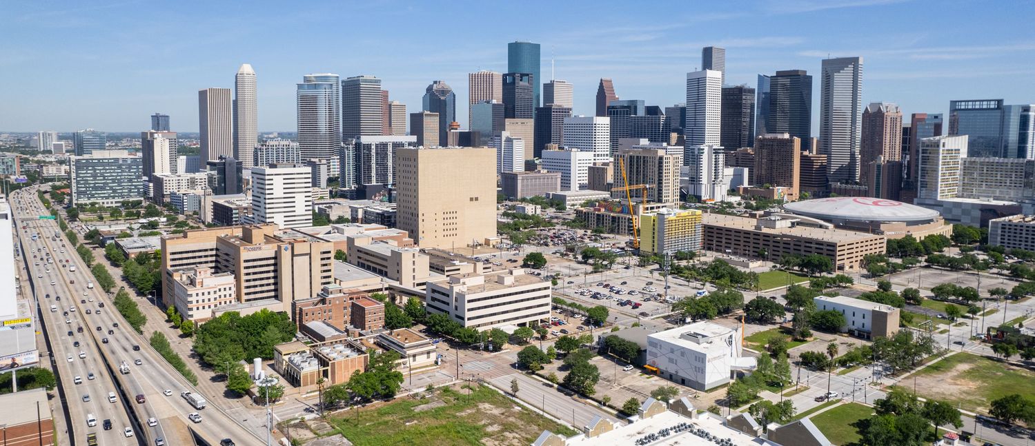 Panoramic skyline view of downtown Denver with modern skyscrapers against a blue sky.