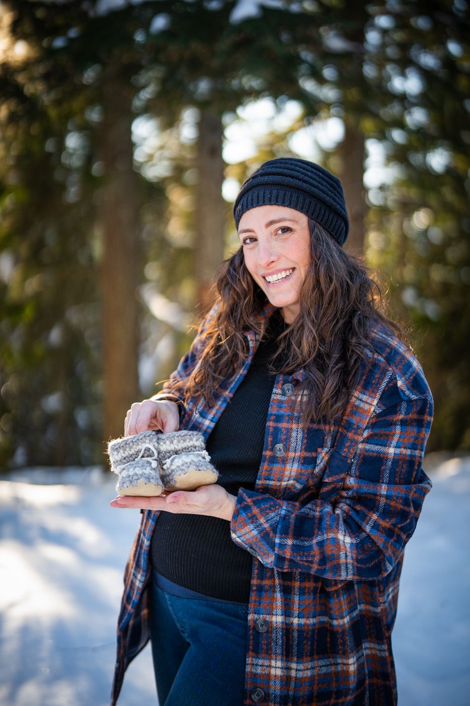 A winter maternity photo session in a snowy forest setting.