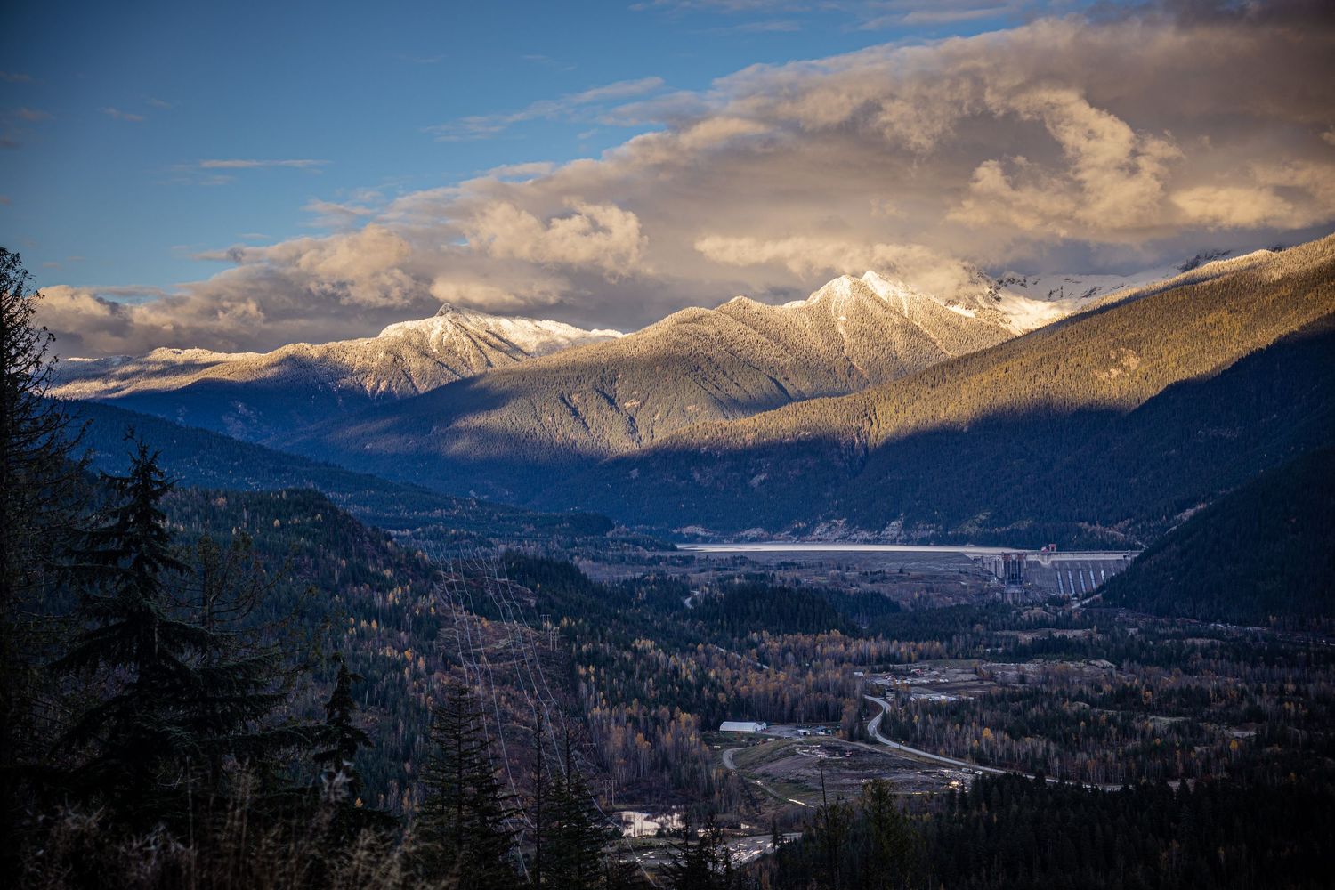 Panoramic mountain landscape with snow-capped peaks and dramatic clouds during sunset in Colorado.