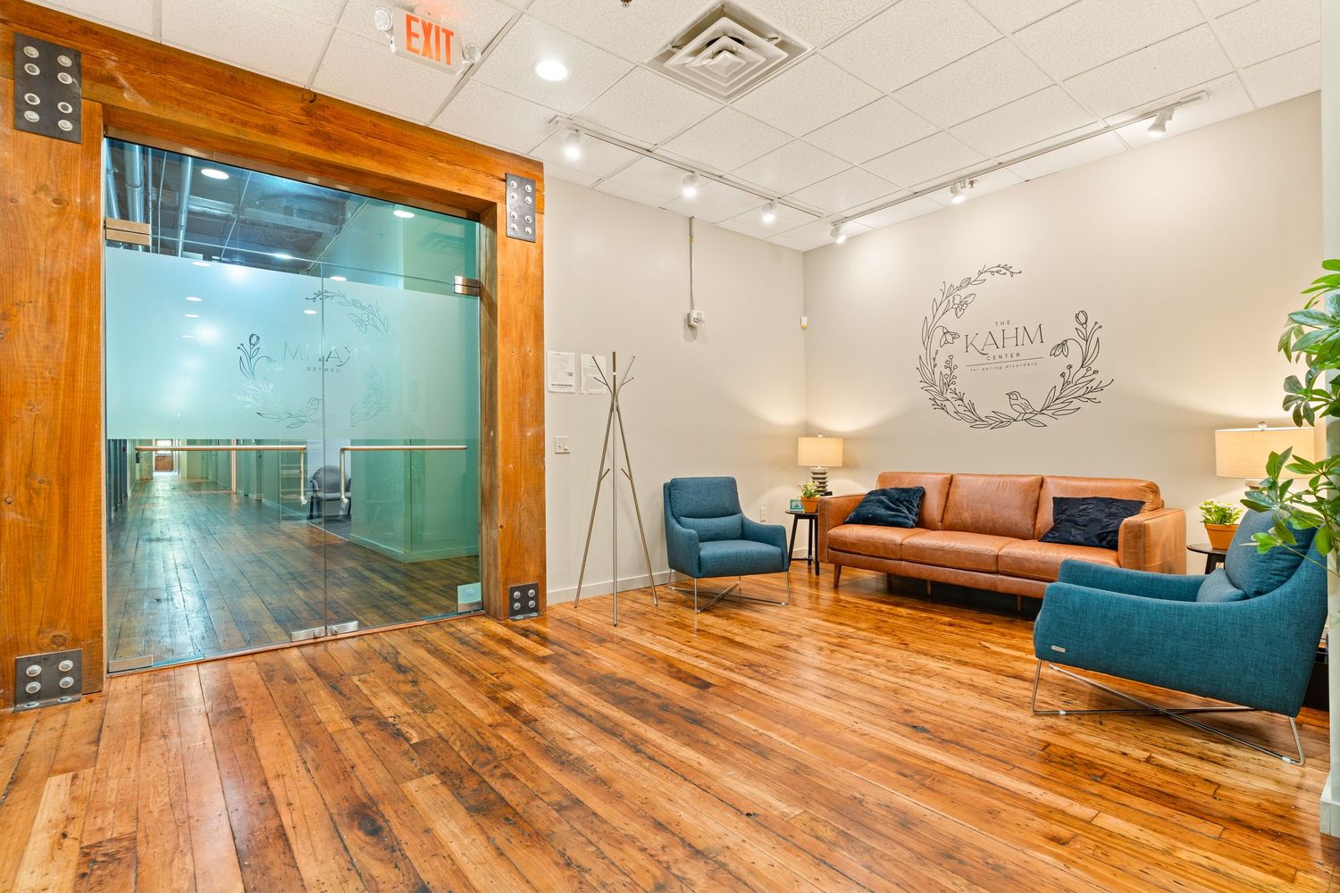 Contemporary office space featuring wooden accents, teal wall panels, and modern furnishings.