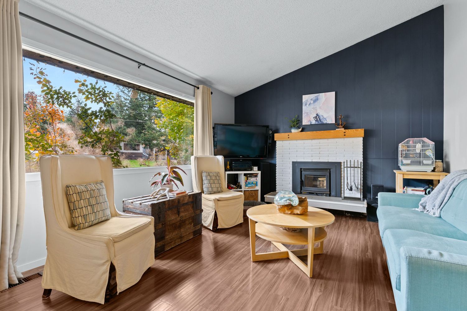 Contemporary living room with navy accent wall, wood floors, and natural lighting.