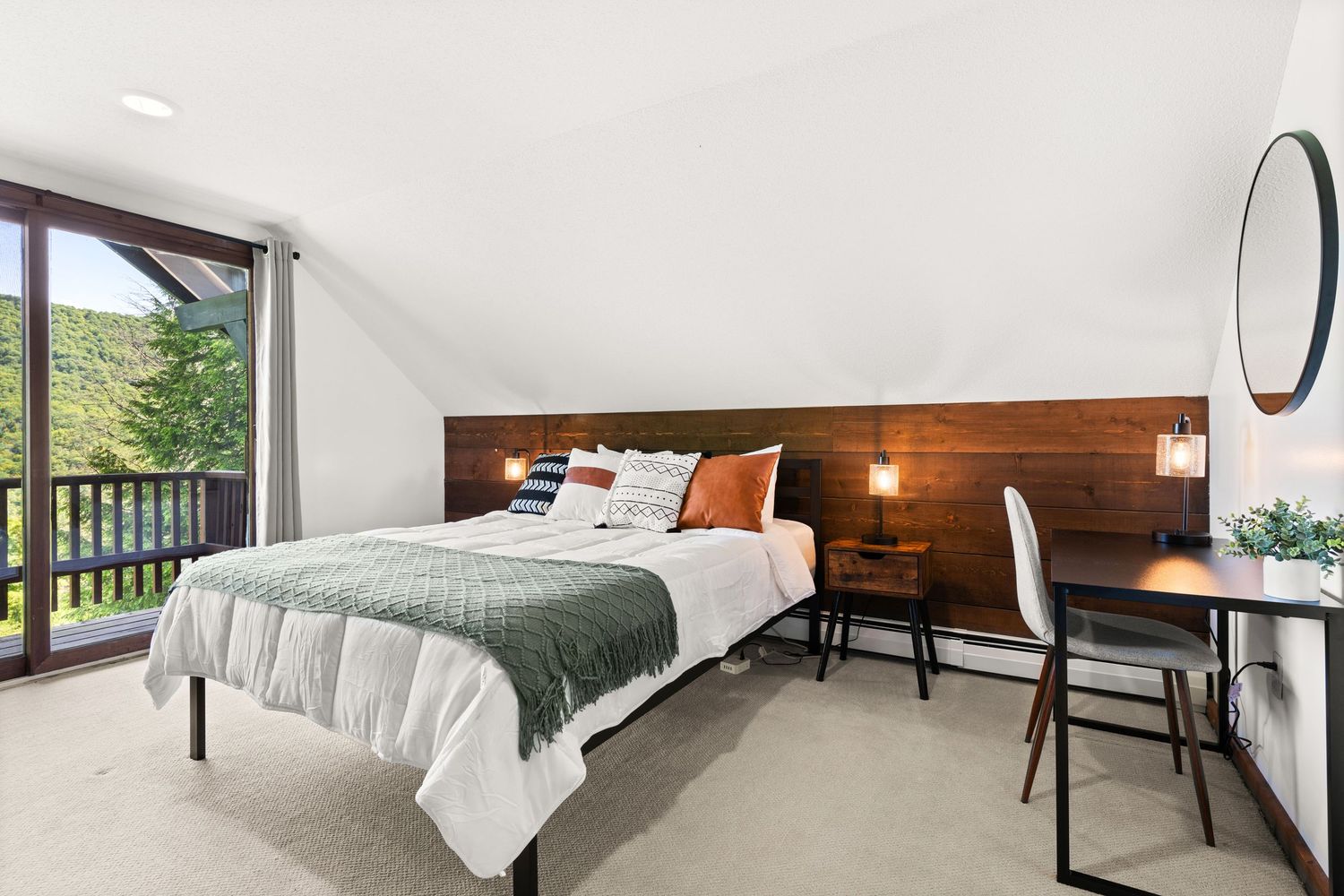 Bright contemporary bedroom with clean white decor, hardwood floors, and mountain views through large windows.