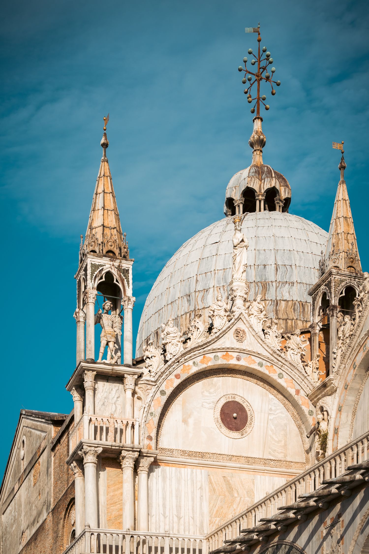 Architectural details of Saint Mark's Basilica in Venice showing ornate domes and Gothic spires against a blue sky.