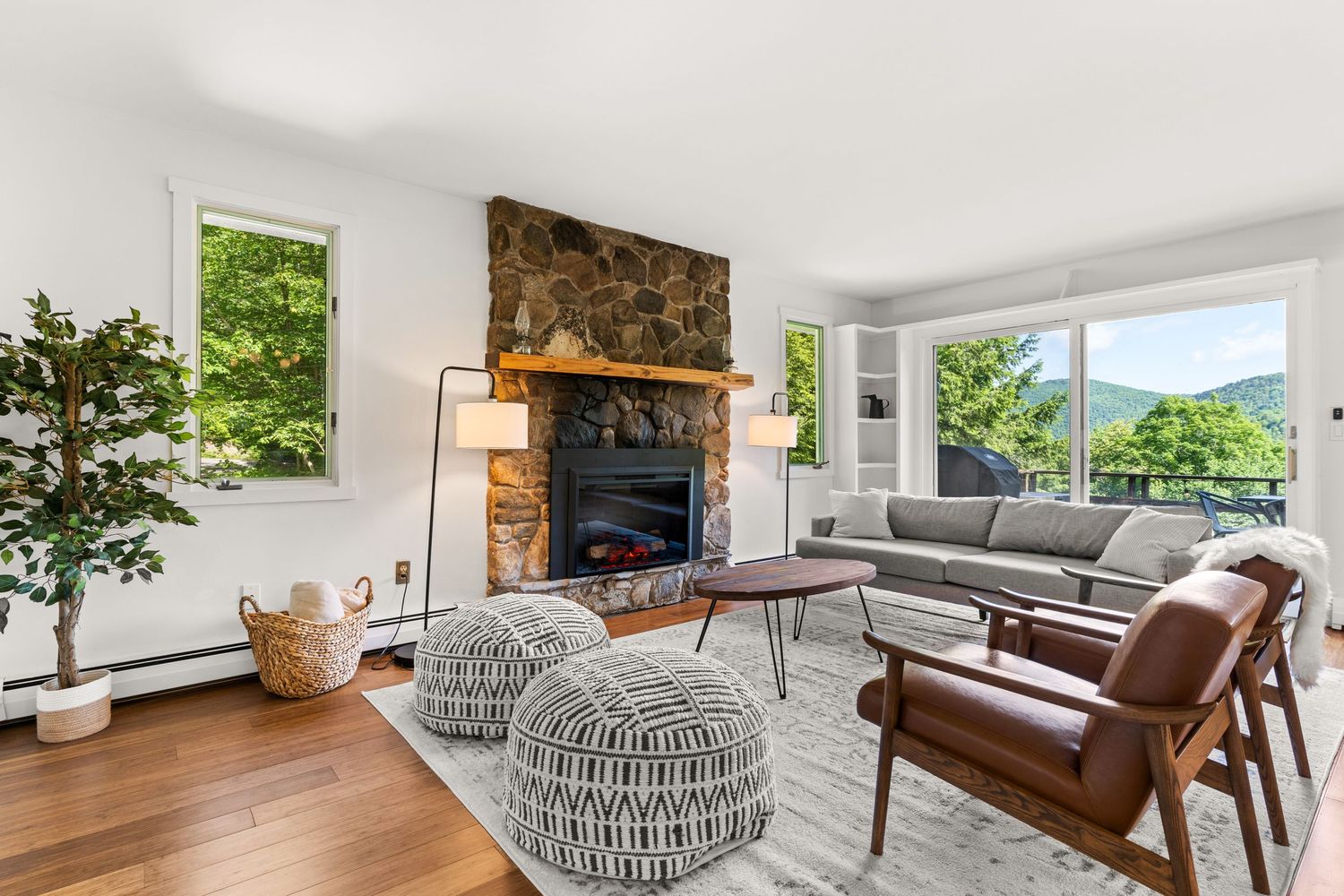 Spacious living room with stone fireplace, modern furniture, and large windows letting in natural light.