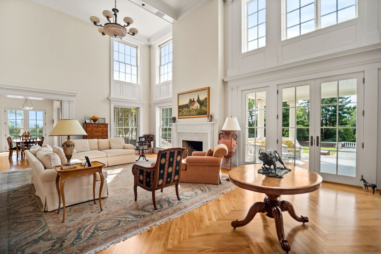Elegant formal living room with classic furniture, white walls, and tall windows offering abundant natural light.