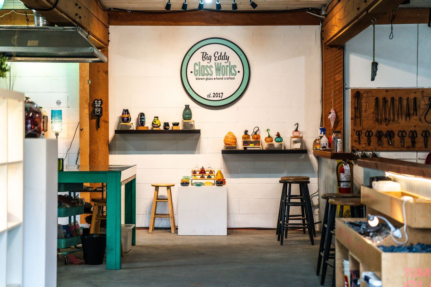 Interior view of a modern brewery taproom with white walls, wooden beams, and green accents.