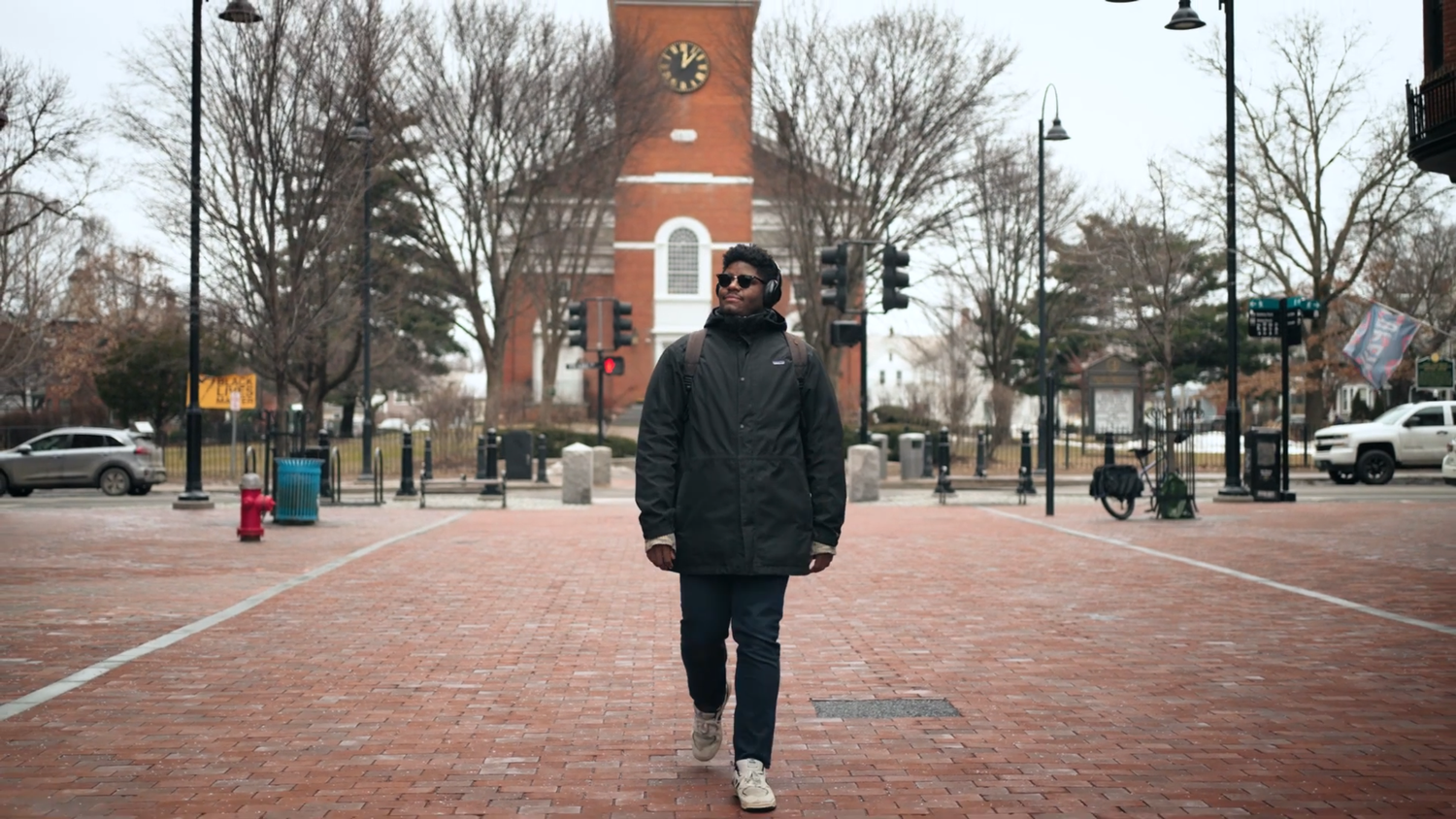 A panoramic view of a brick clock tower and pedestrian walkway on a college campus during winter.