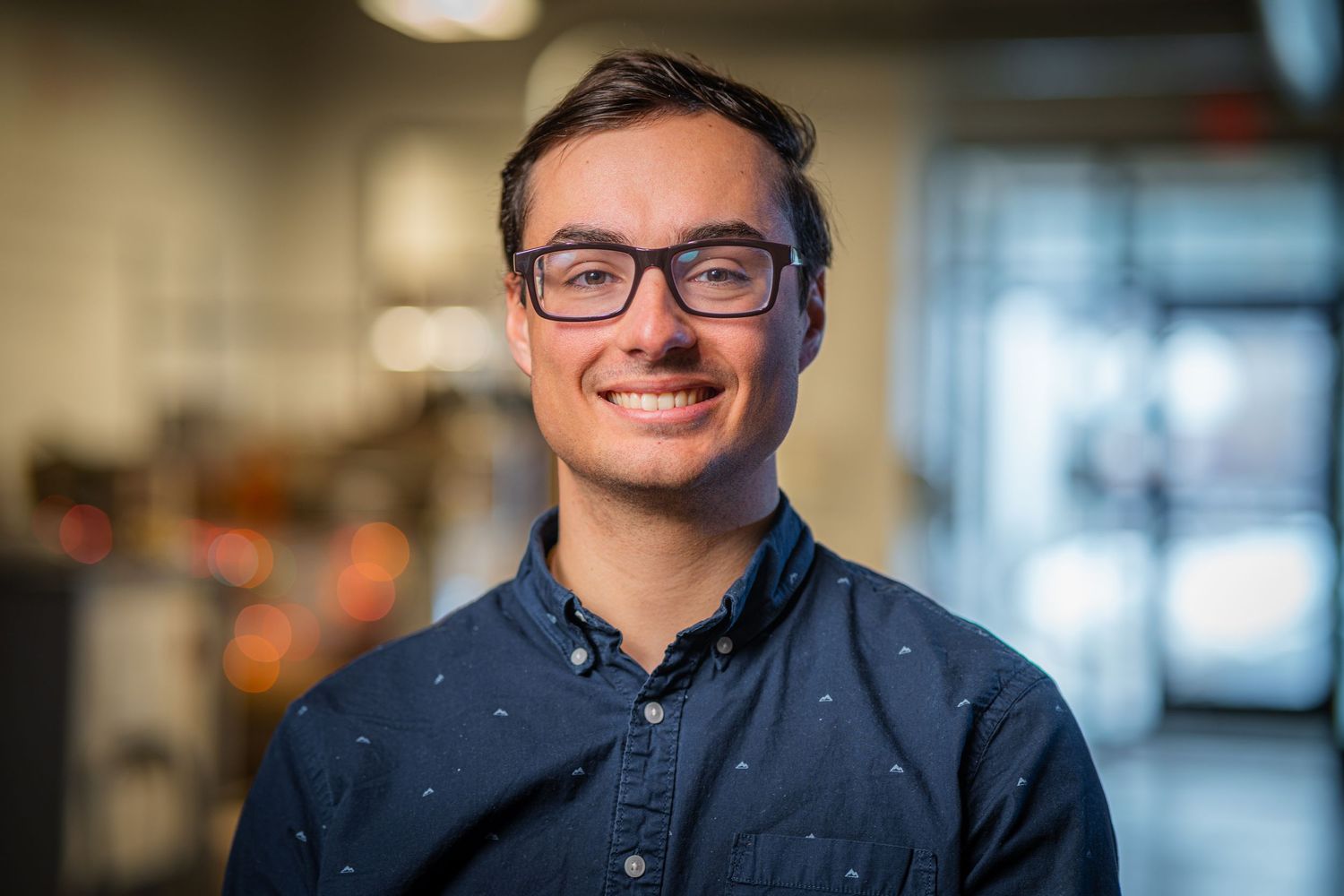 Professional headshot series of a person in glasses and button-down shirt shown at different angles in an office setting.