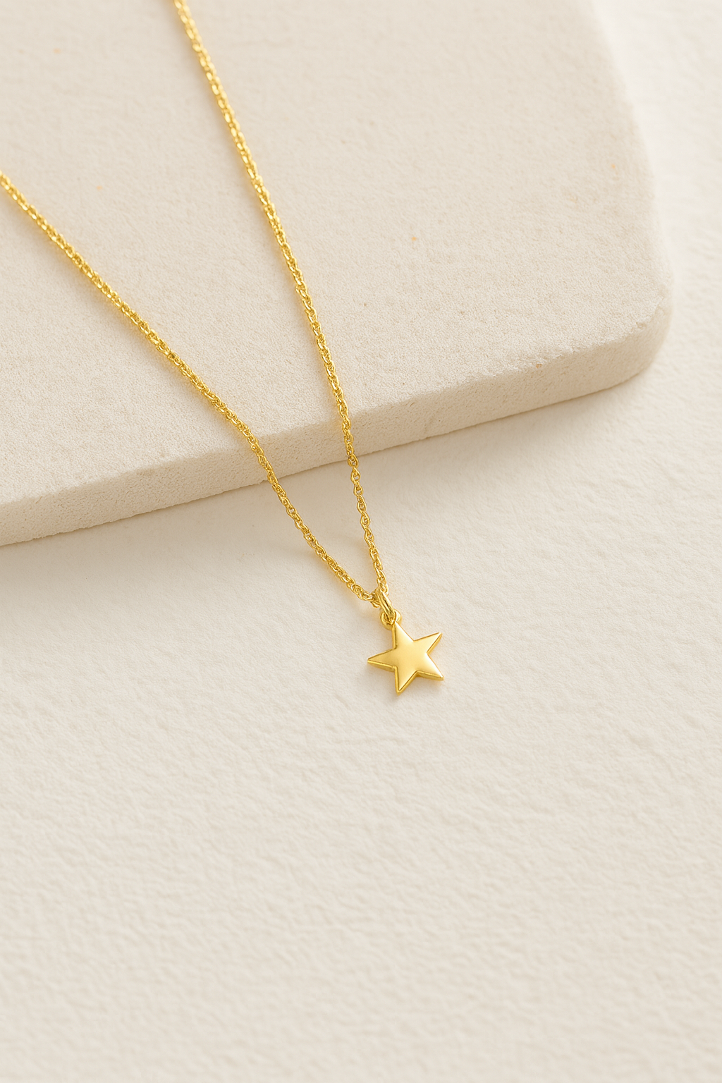 Collar dorado con colgante de corazón sobre fondo crema. Fotografía de producto minimalista para joyería online.