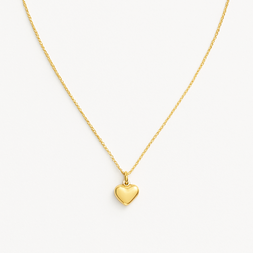 Collar dorado con colgante en forma de corazón sobre fondo blanco. Fotografía de producto minimalista para e-commerce de joyería.