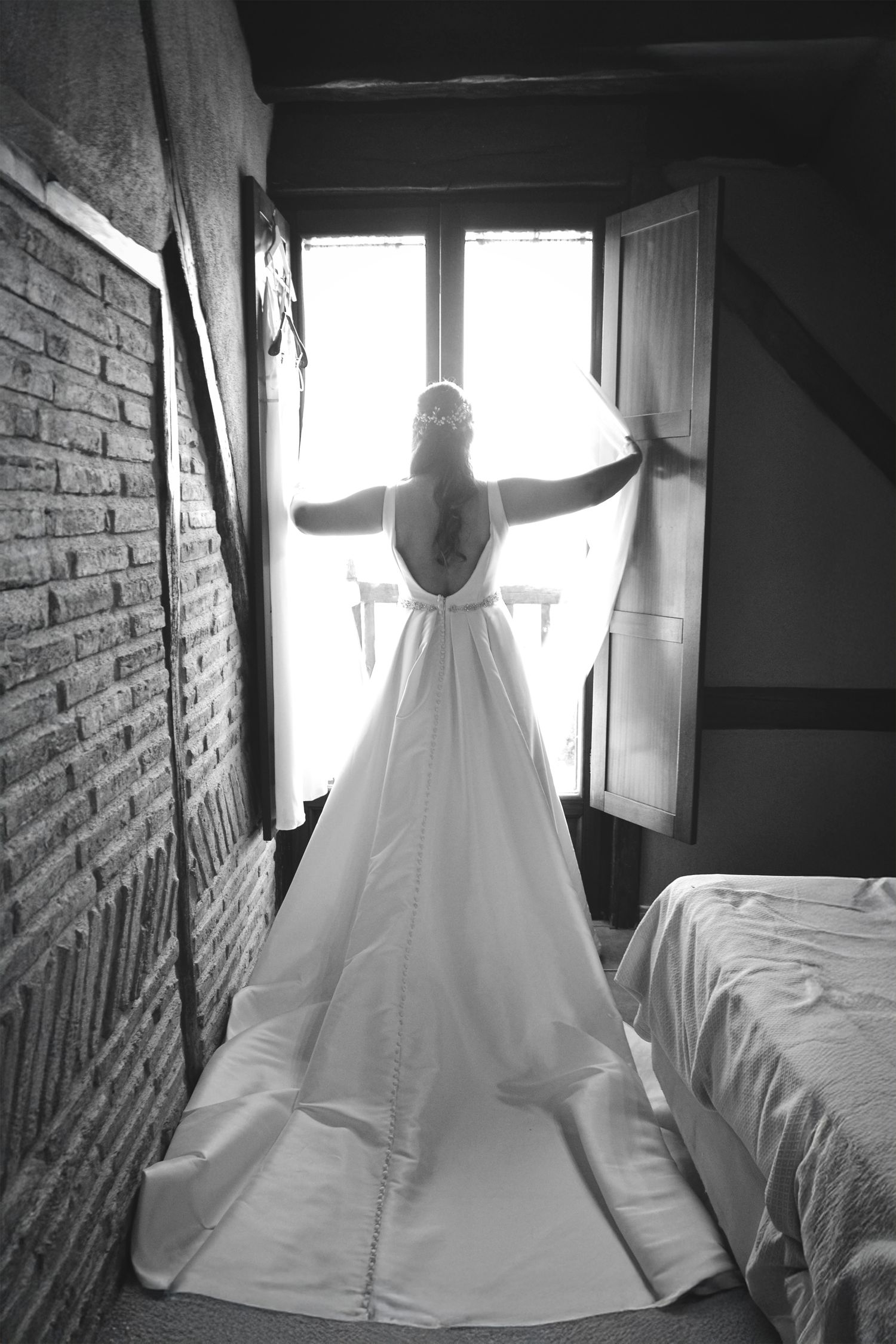 Fotografía de novia de espaldas mirando por la ventana. Imagen elegante y luminosa de boda en Bilbao.