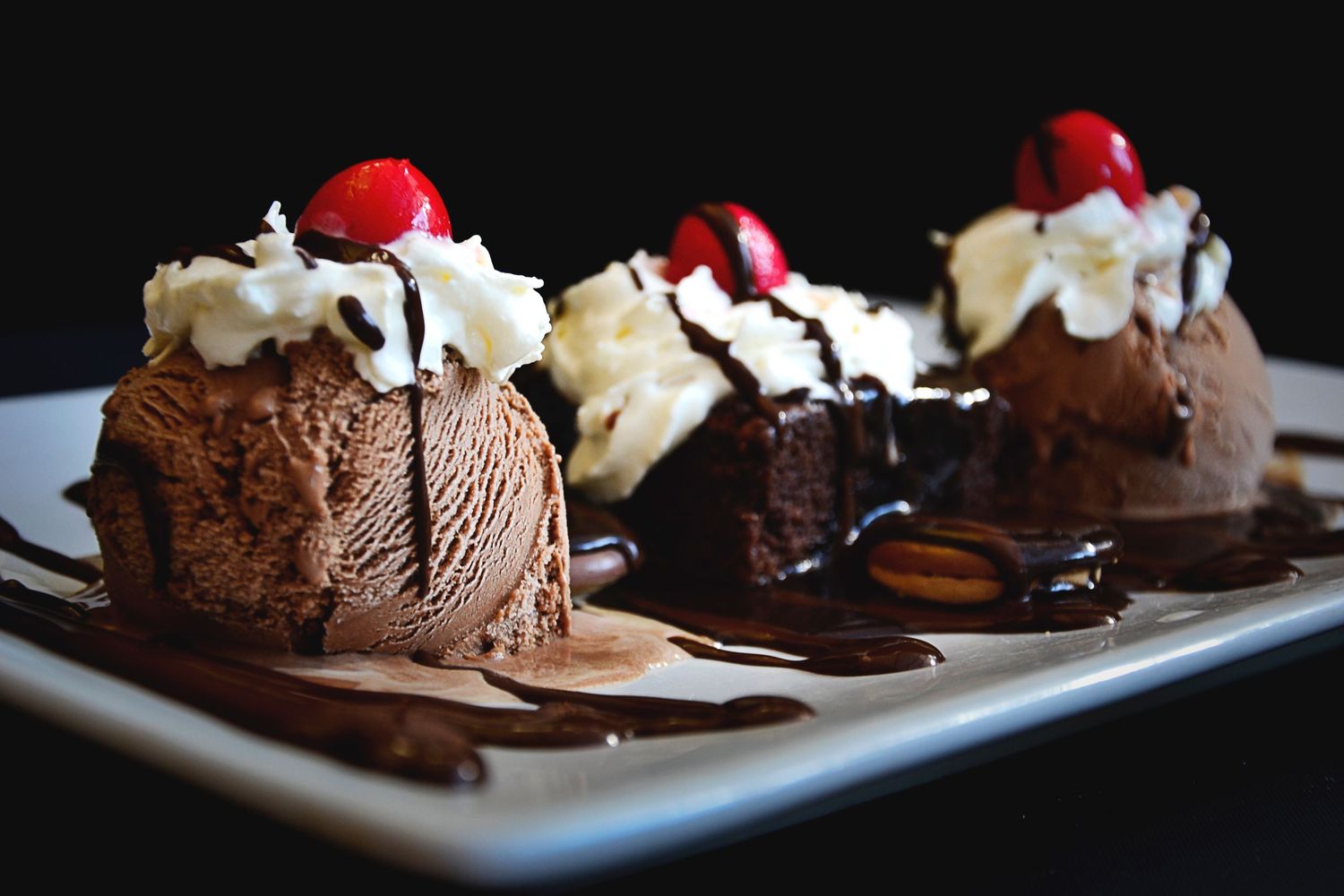 Postre de chocolate con nata y cereza, fotografía gastronómica profesional.
