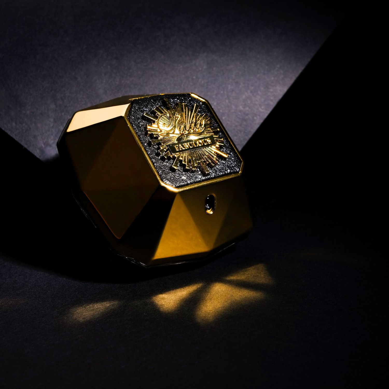 Fotografía de producto de perfume con iluminación dramática sobre fondo oscuro, imagen publicitaria para marca de lujo.