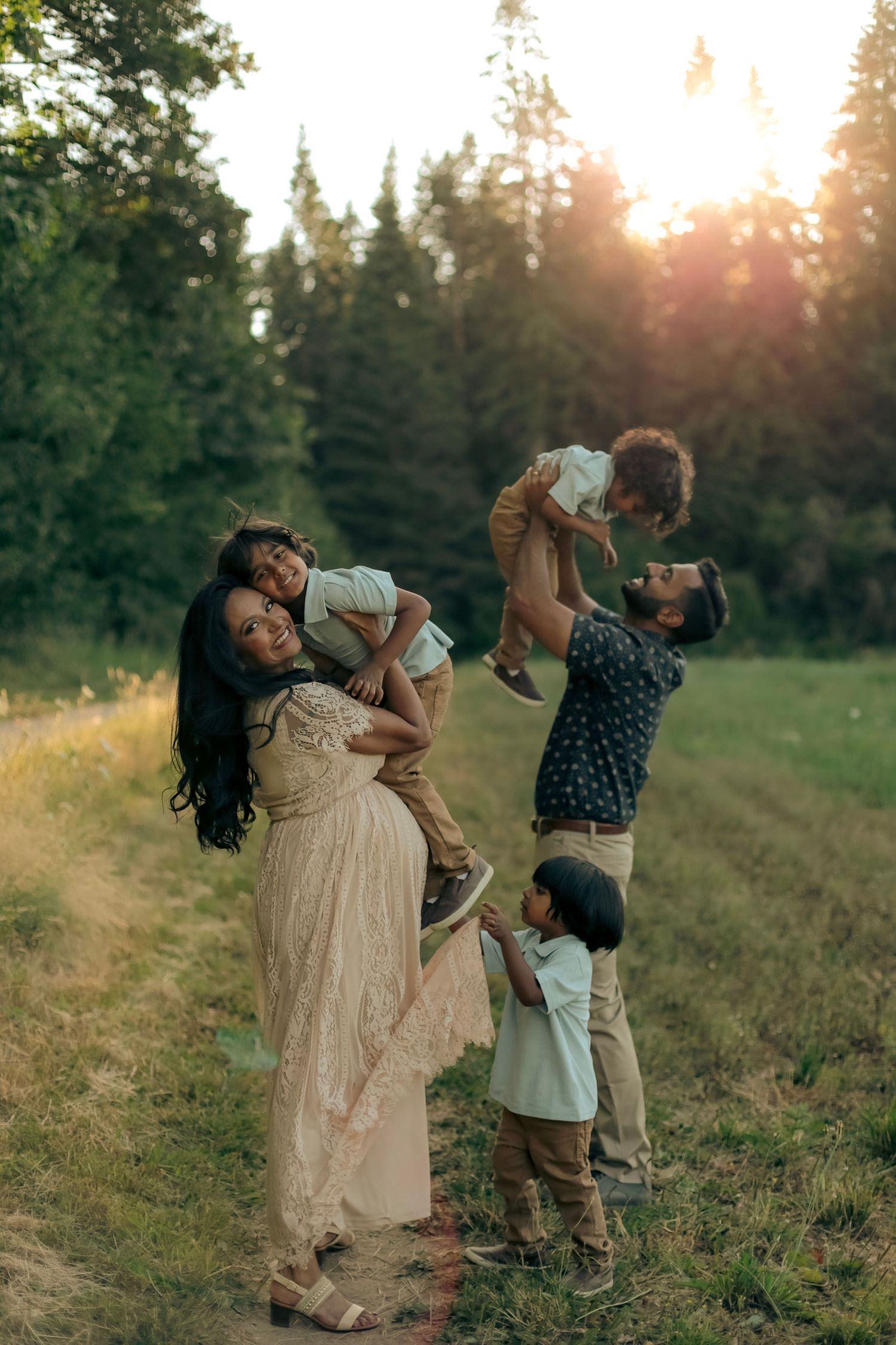 A family of five playing together in a field with a forest in the background.