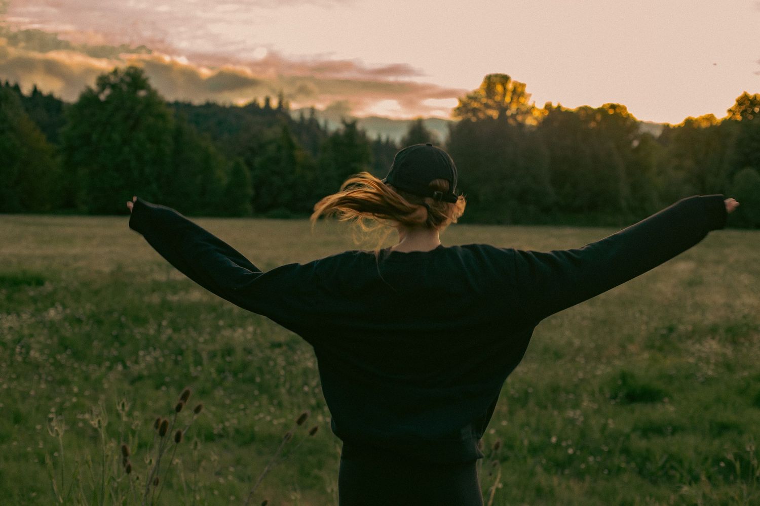 A woman twirls around in a sunset-lit field in Tillamook, Oregon.