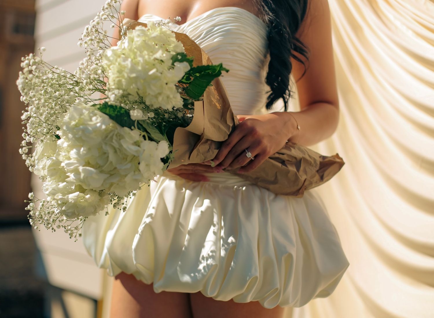 A bride-to-be wears a white dress and hold beautiful white flowers