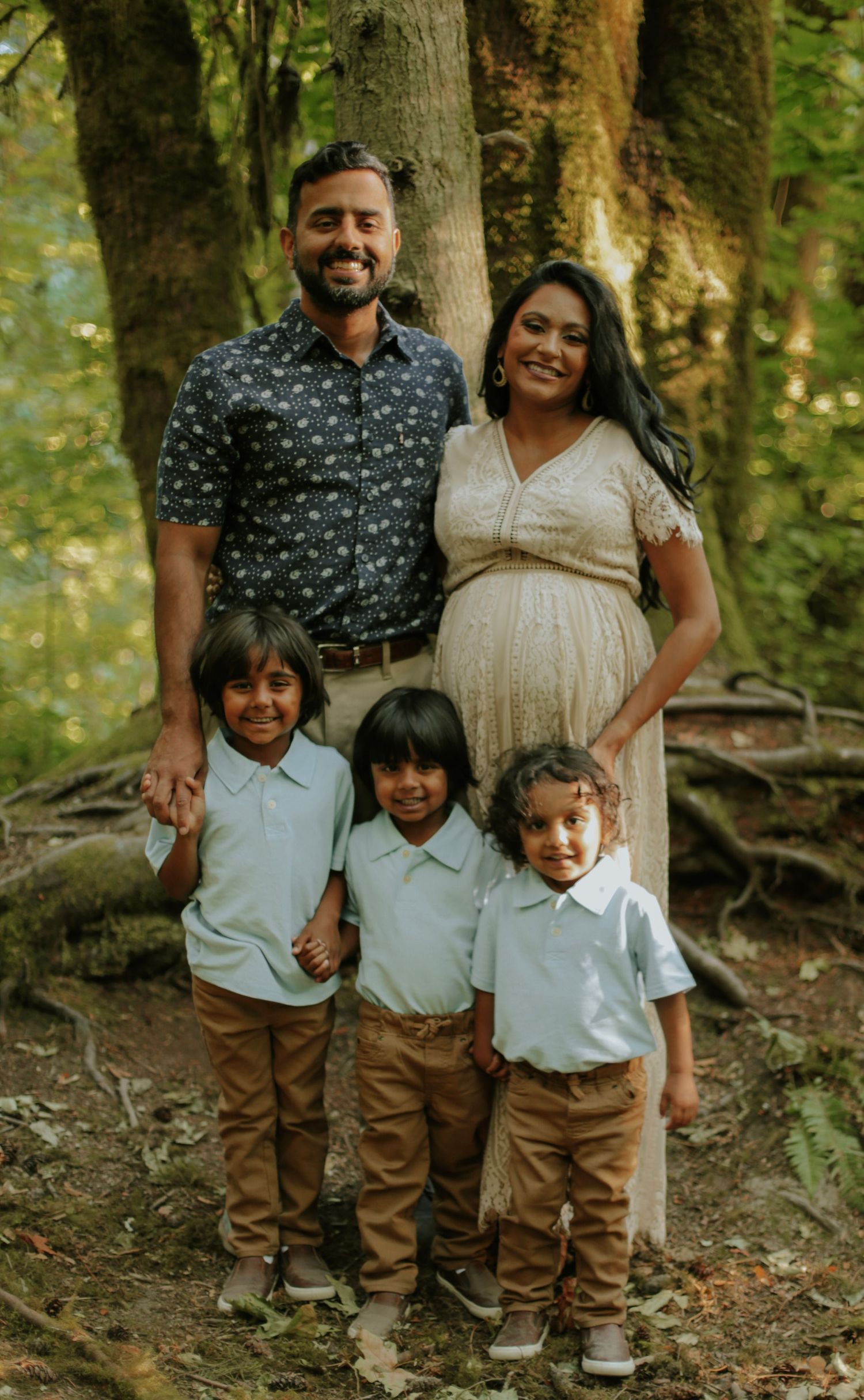 A family photo showing a mother, father, and three sons in a green, mossy, forest.