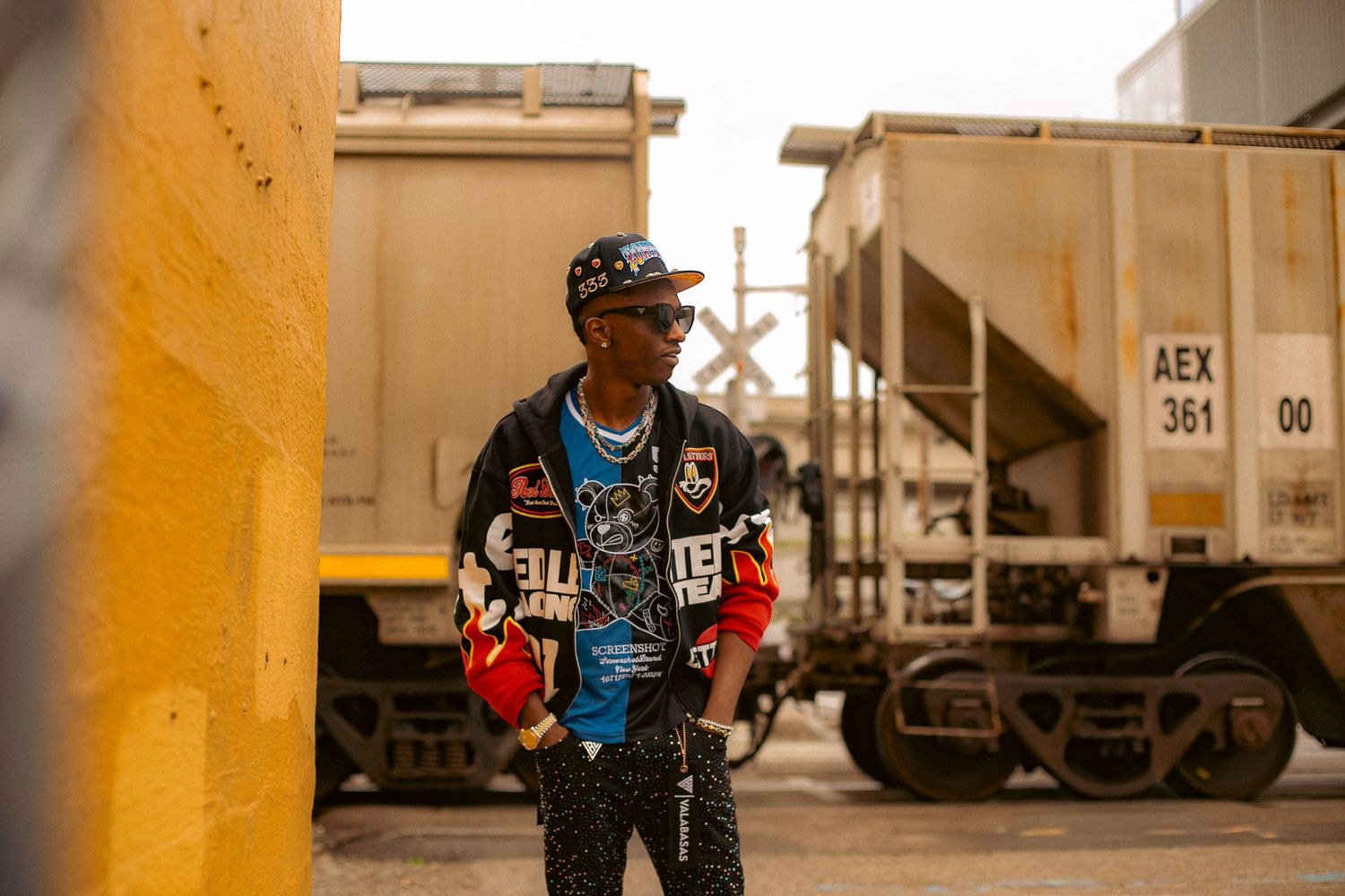 A man poses for an urban modeling photoshoot in Portland, Oregon with a train passing behind him