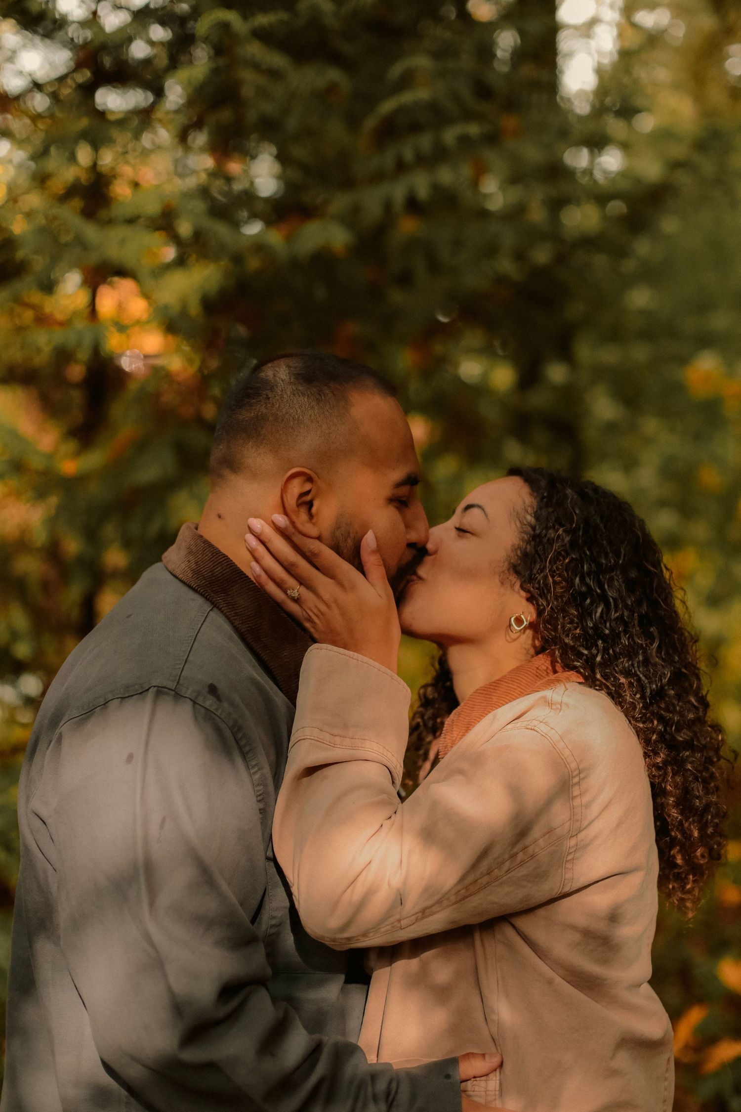 Couple kissing, forest background with the sun shining through the trees in a park in Portland, Oregon