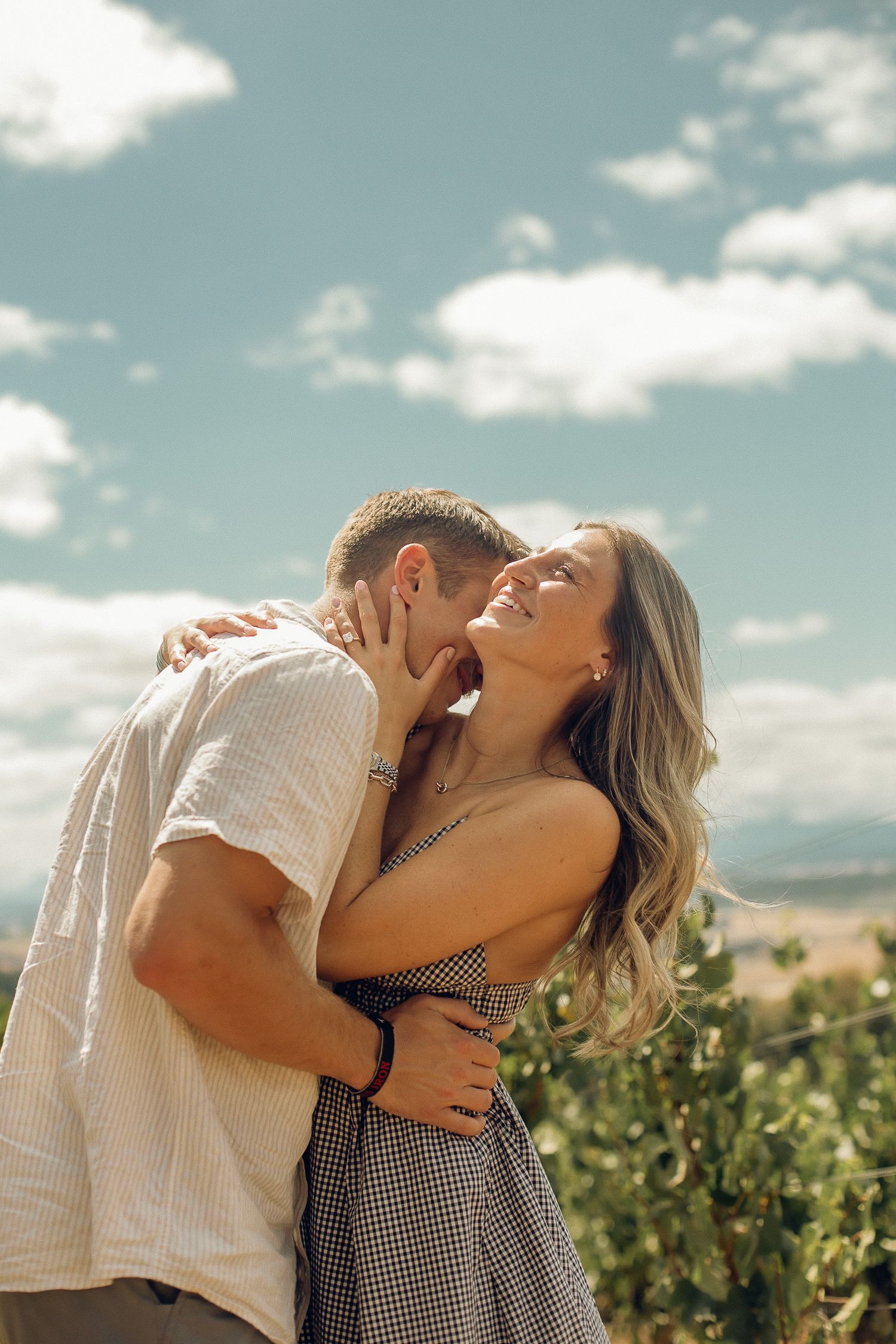 A newly engaged couple embraces in a warm, sunny, Oregon winery.
