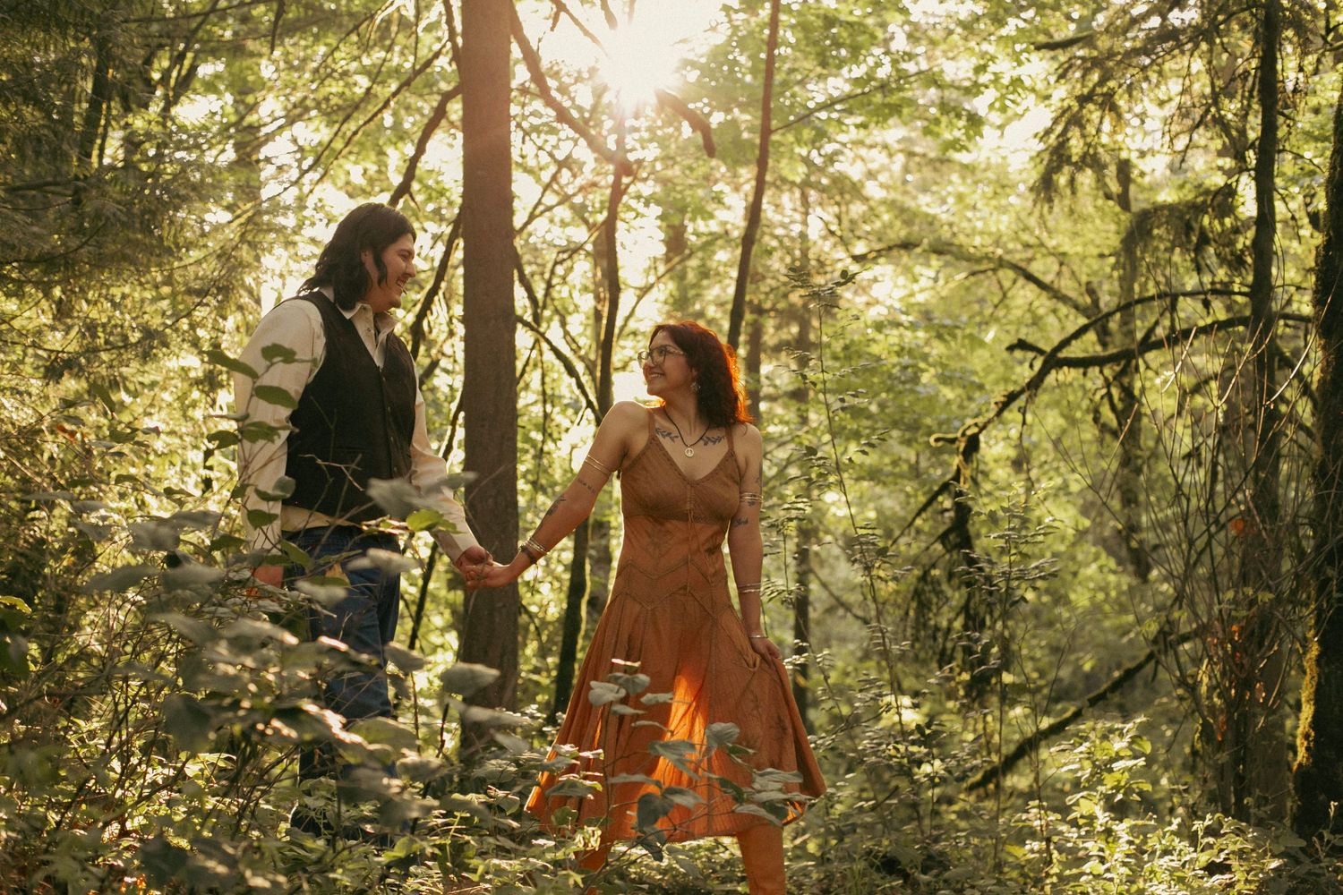 A newly engaged couple walk hand-in-hand through a forest in Oregon for an engagement/proposal photoshoot