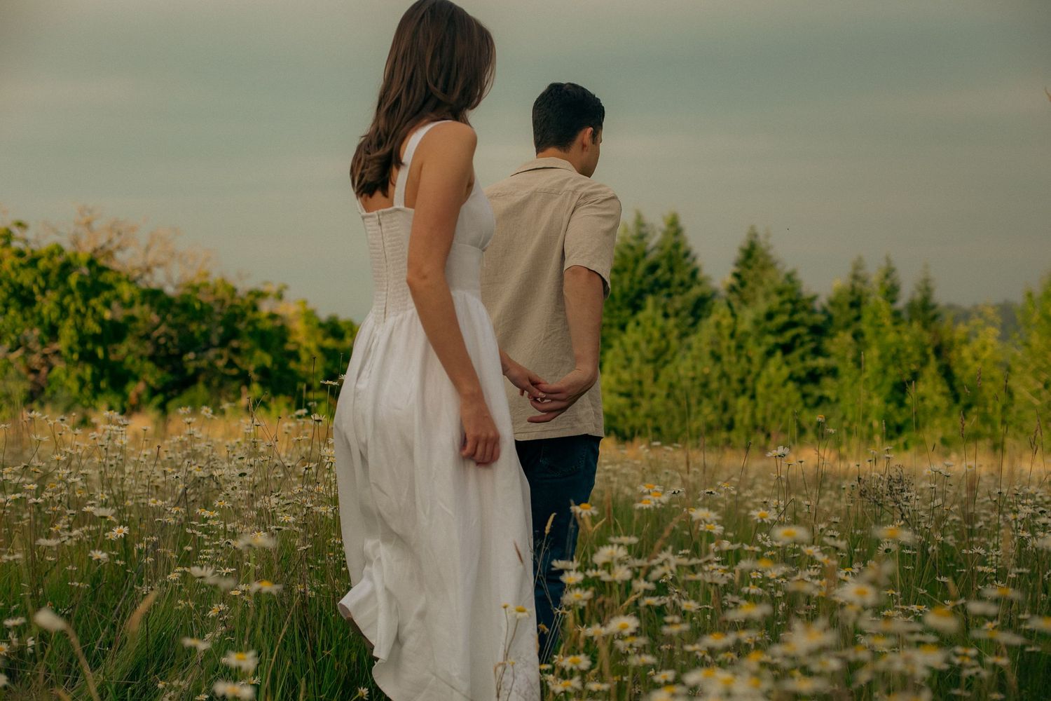 A couple walks through a field of wildflowers for an engagement photoshoot in Portland, Oregon