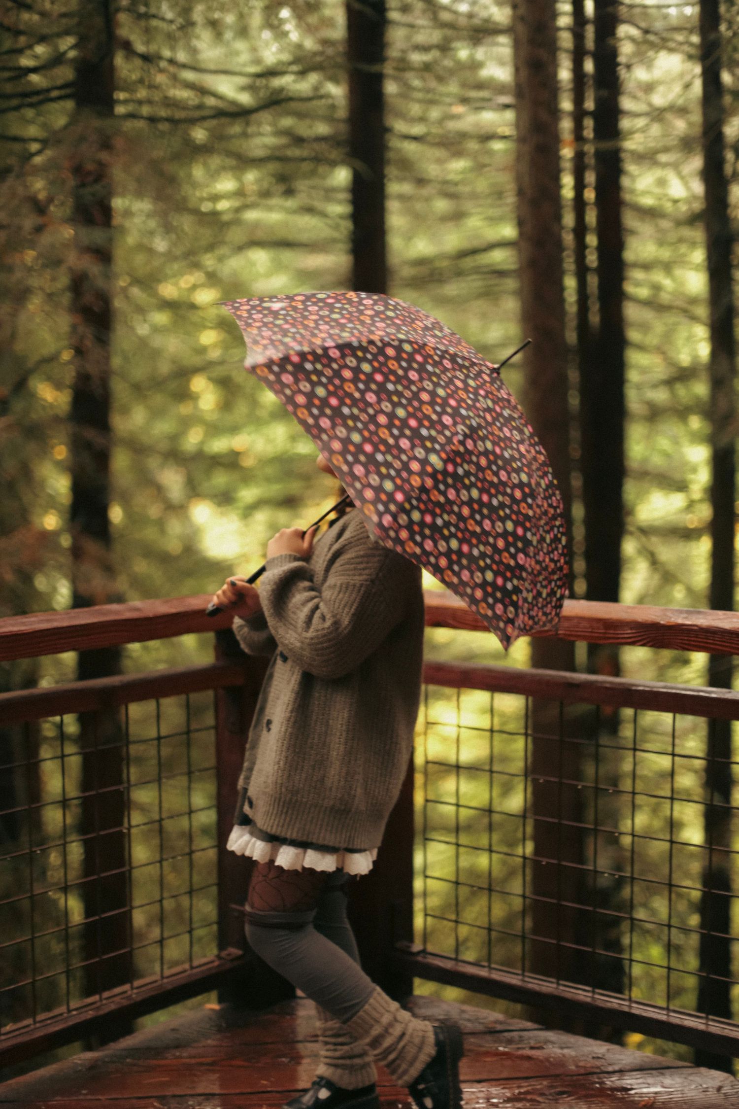 A young woman twirling a polkadot umbrella in a forest setting - a high school senior photoshoot