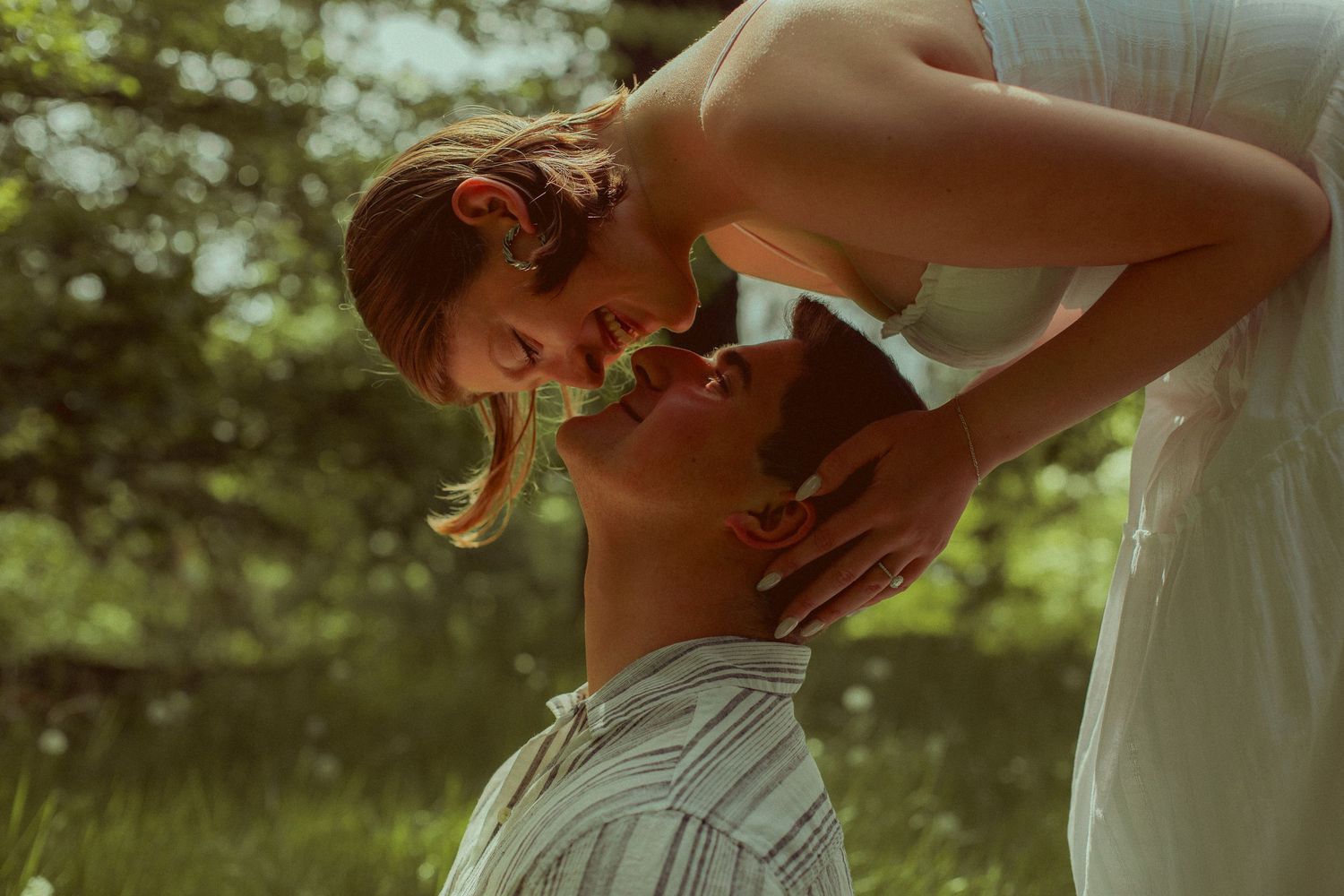 A woman leans her head over her partner's and smiles playfully as they pose for an engagement photoshoot in Portland, Oregon