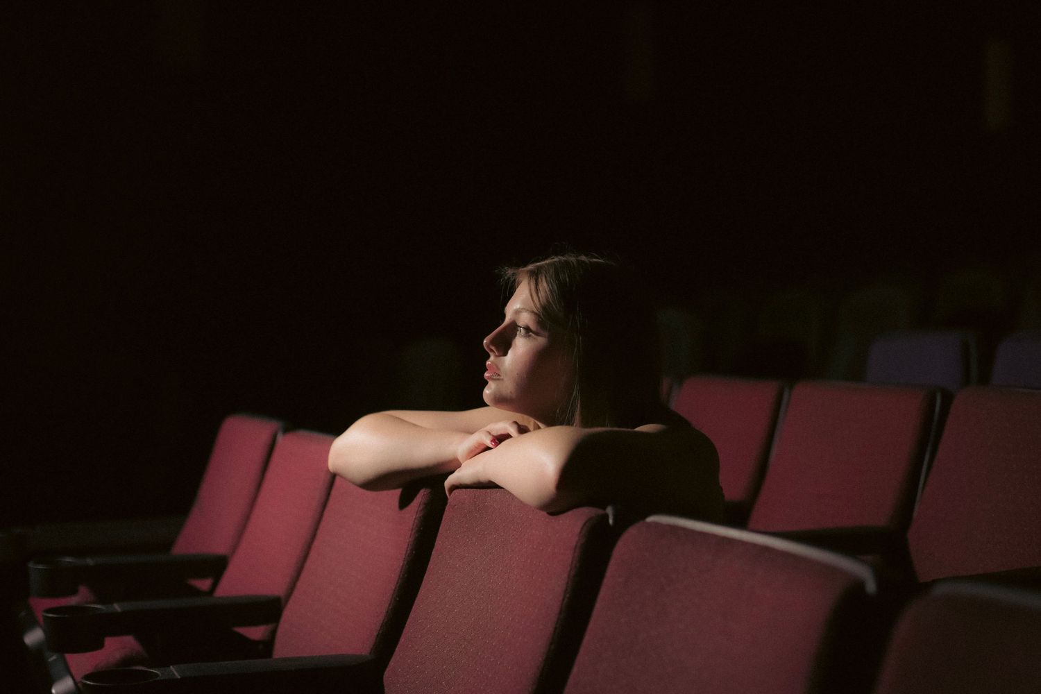 young woman in a vintage theater seat looking at the screen