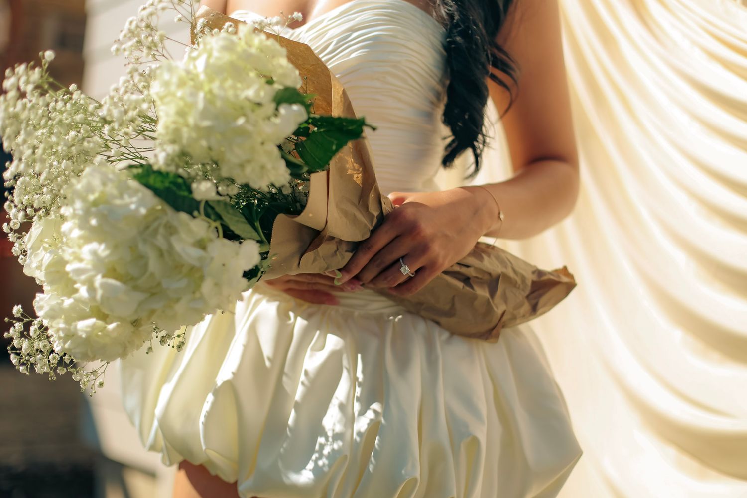A bride-to-be wears a white dress and hold beautiful white flowers