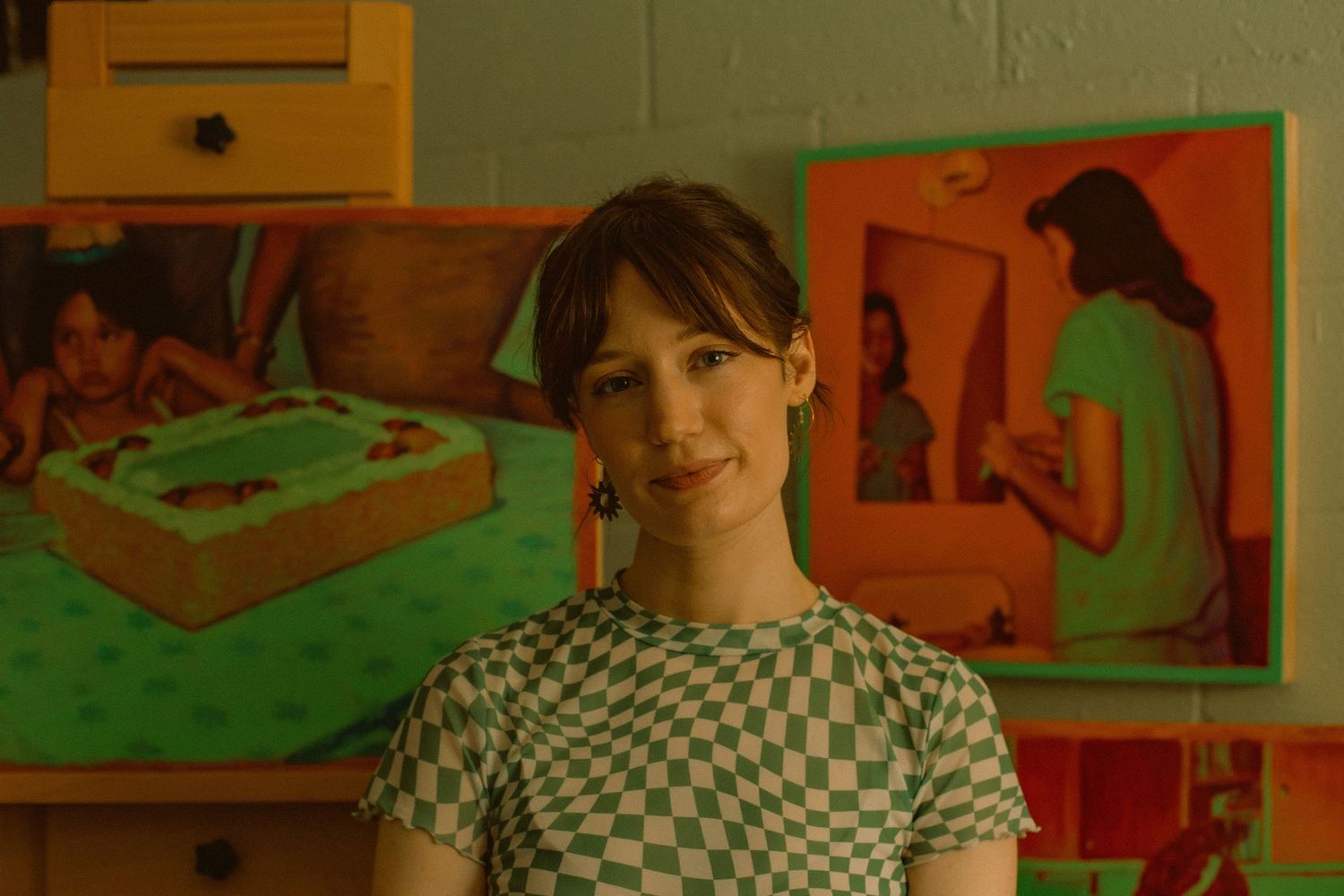 A woman poses in front of her paintings in her art studio for a solo portrait session in Portland, Oregon