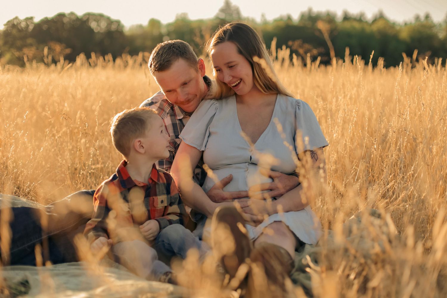 A maternity family photoshoot in a sunny field