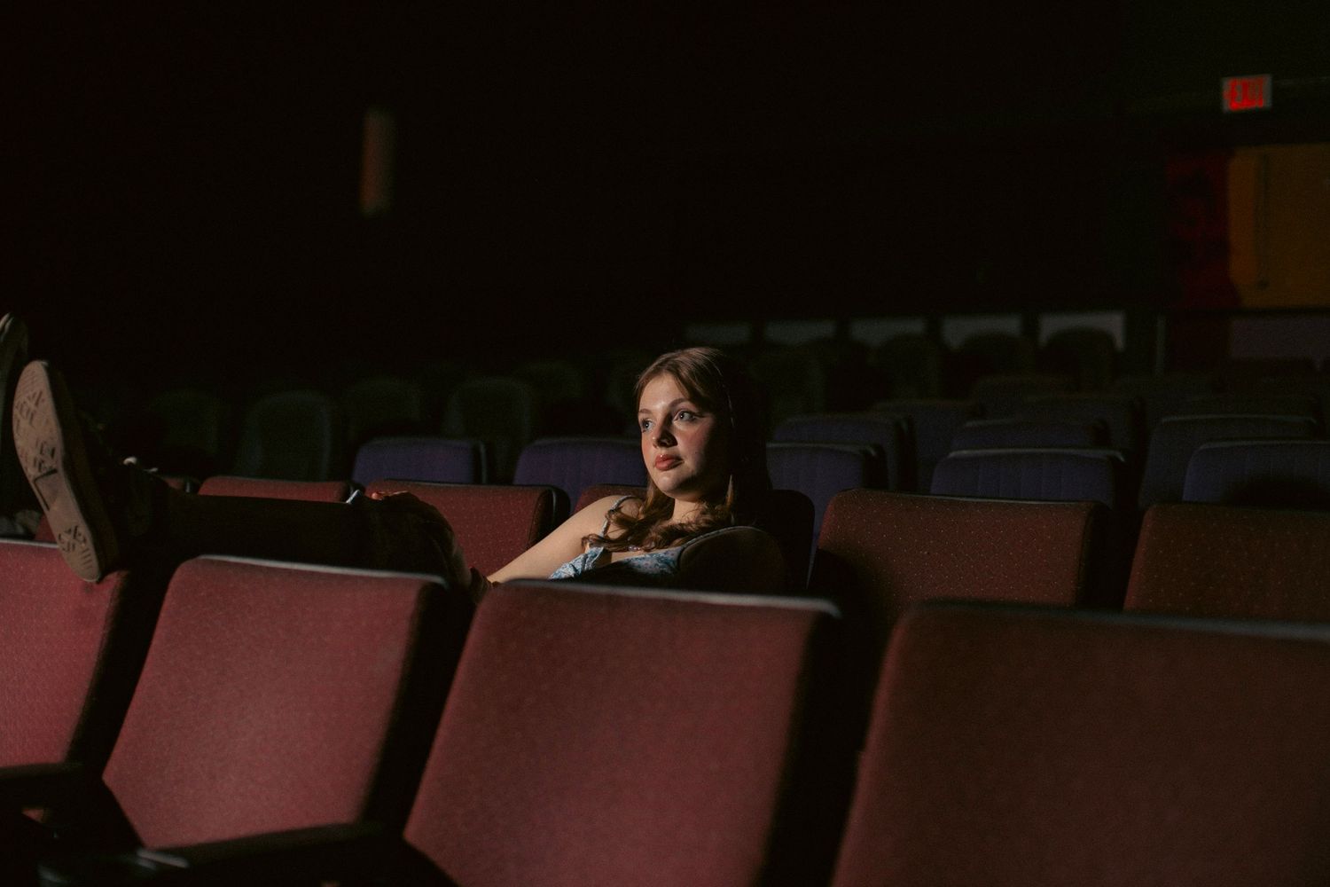 young woman in a vintage theater seat looking at the screen