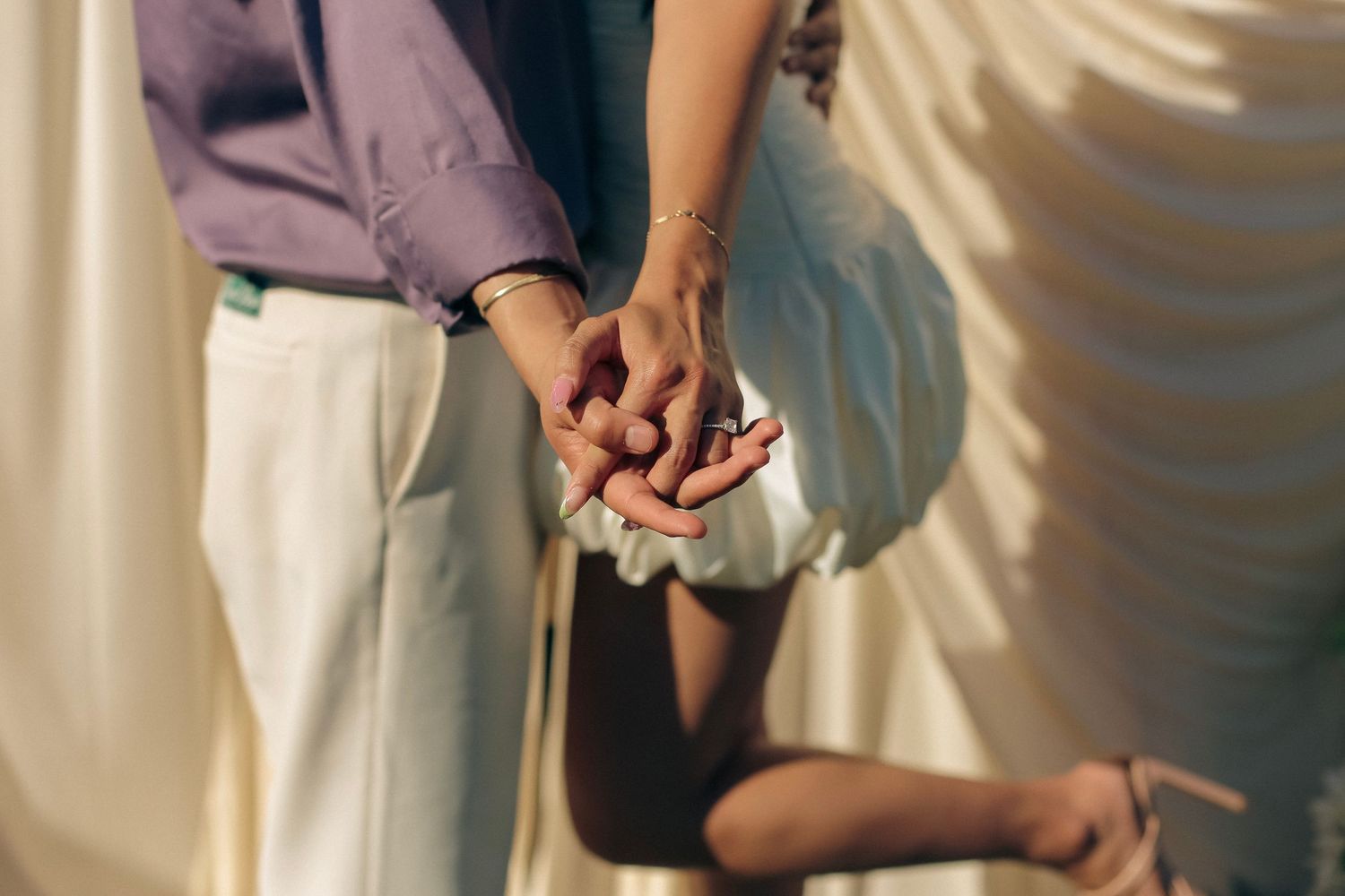 A man and woman holding hands - the woman is in a white poofy dress.