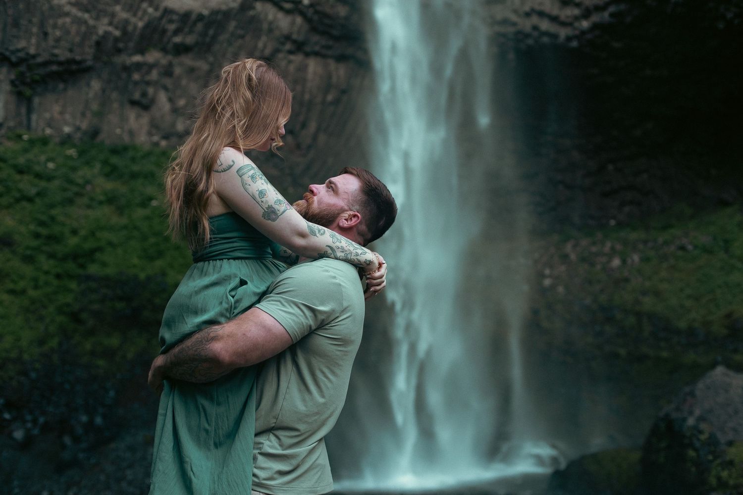 A man picking up his fiancé in front of an Oregon waterfall for an engagement photoshoot
